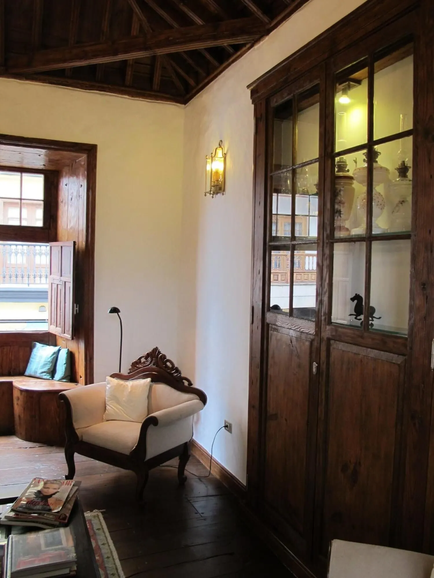 Hotel Emblemático San Agustín: A cozy room with a wooden ceiling, a large cabinet with glass doors
