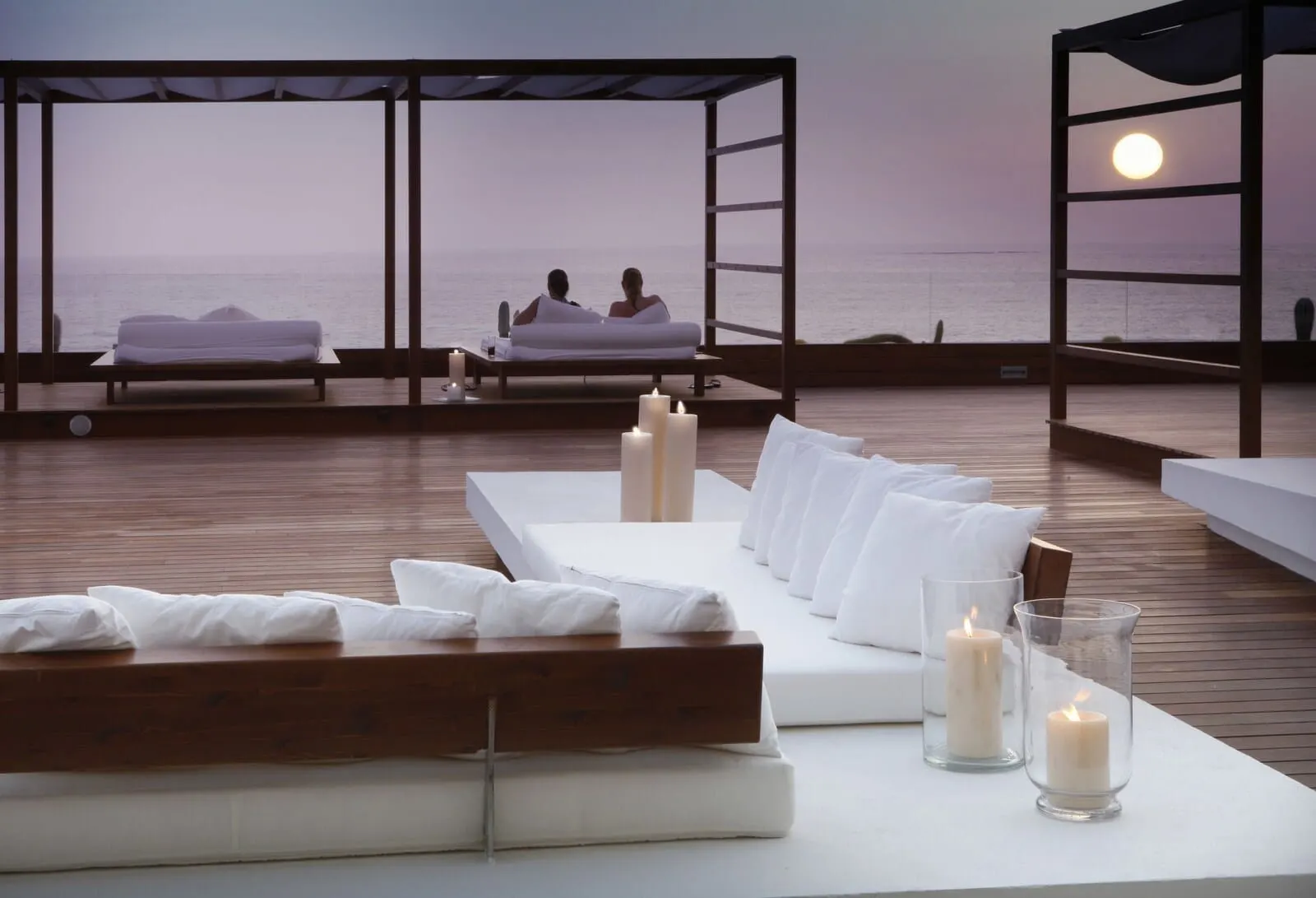 H10 Gran Tinerfe: A serene outdoor seating area with a wooden deck, white cushioned sofas, and candles