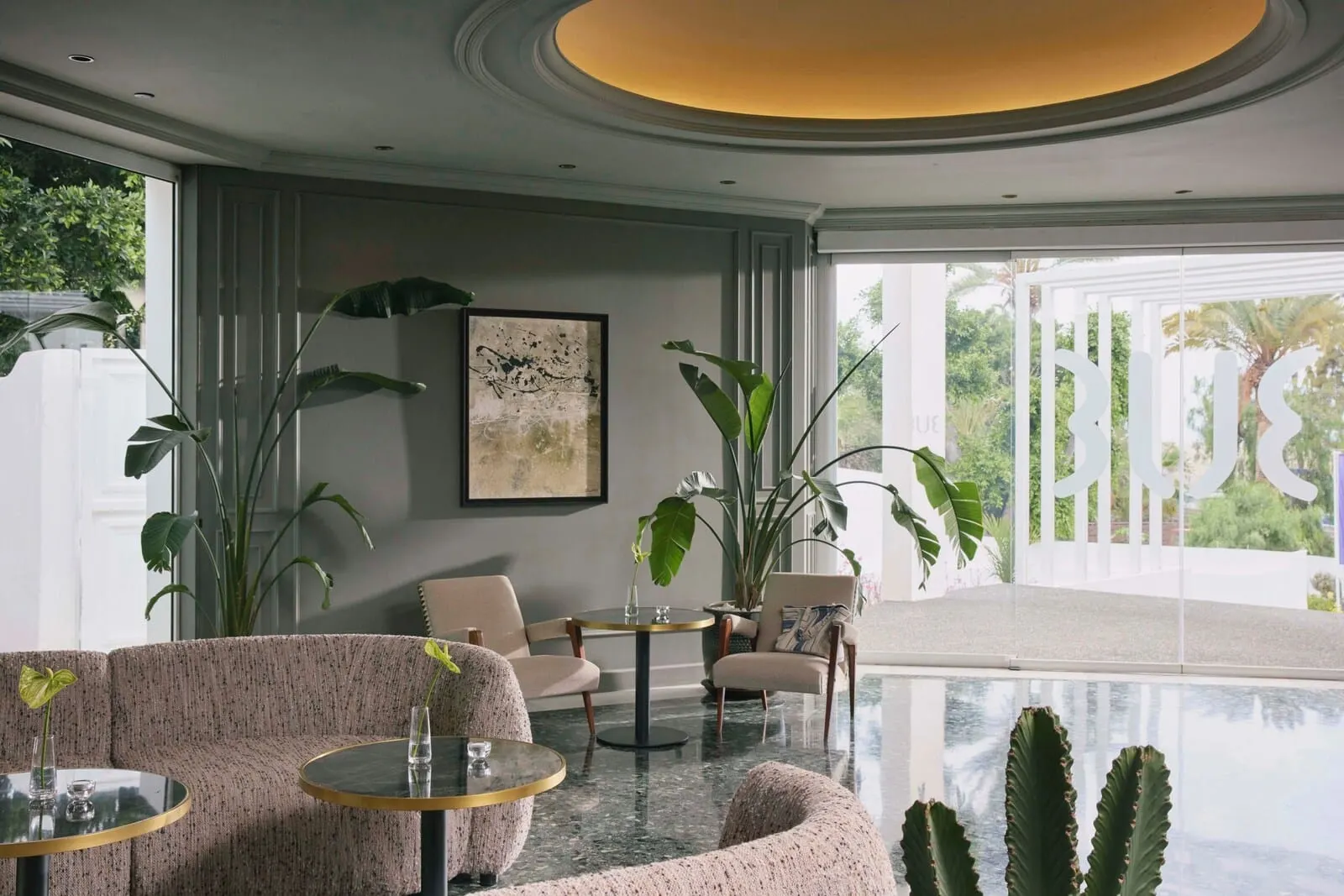 TUI BLUE Atlantic Hills: A modern interior with a sofa, chairs, a round table, and large plants