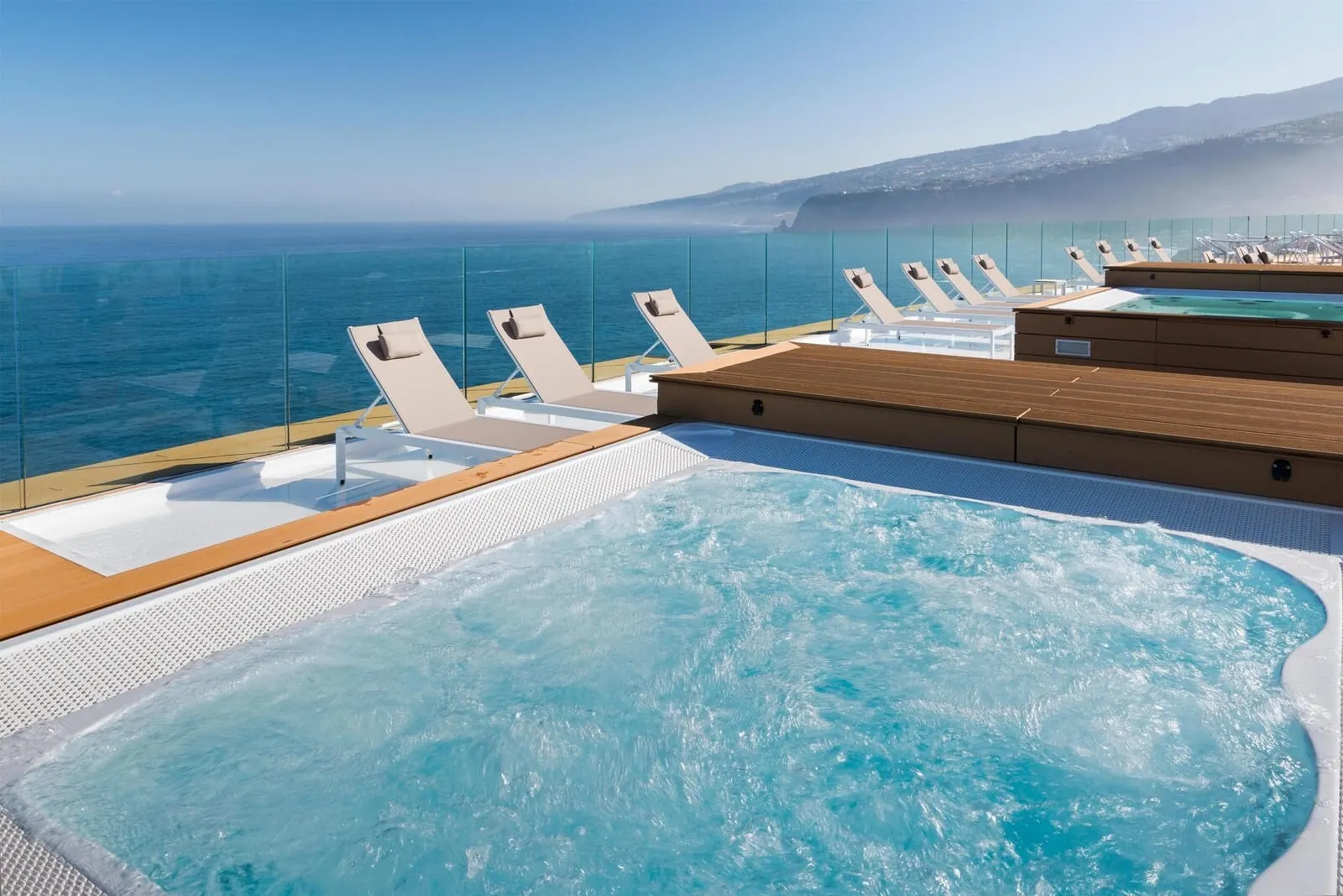 Atlantic Mirage Suites & Spa: A poolside area with lounge chairs and a view of the sea