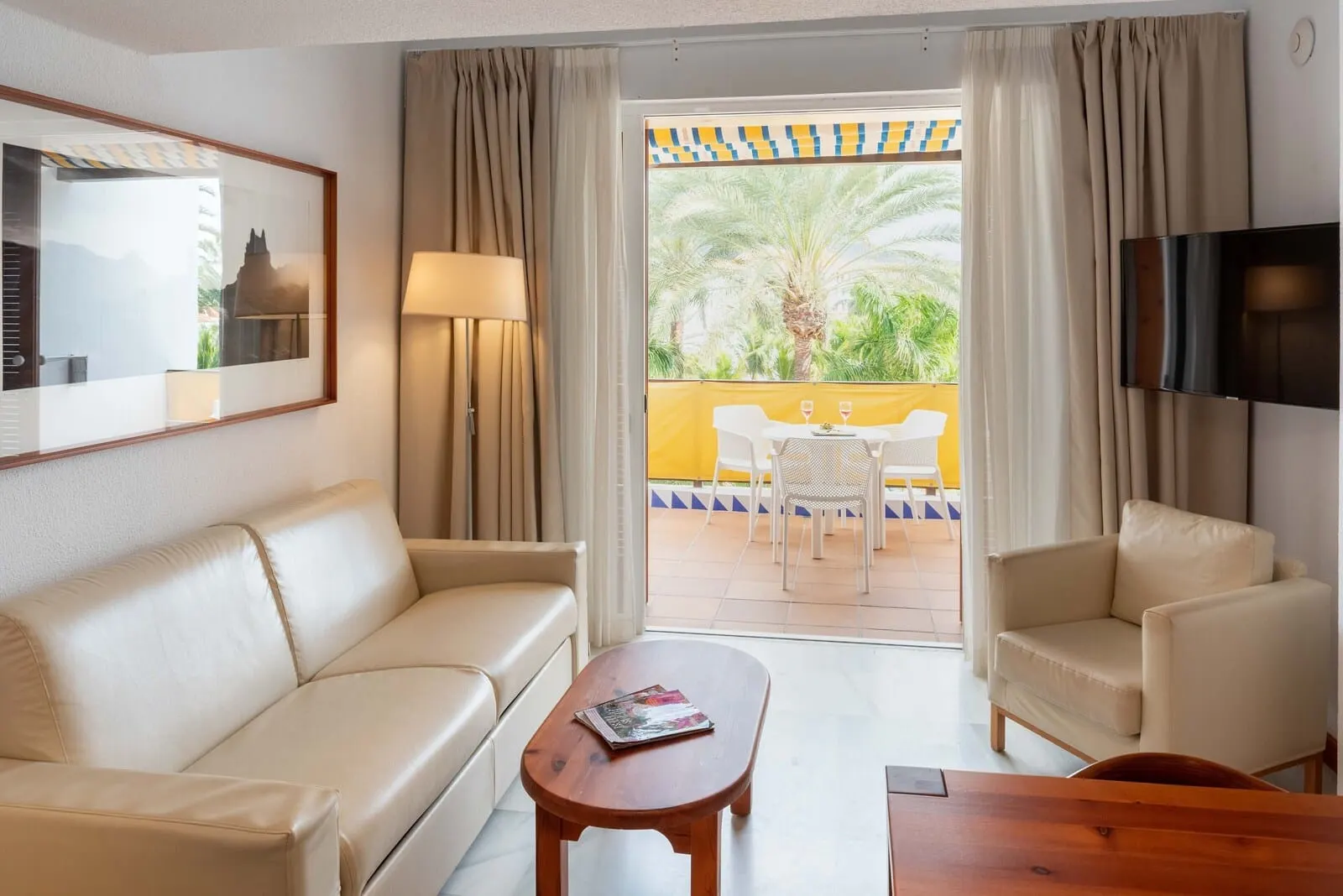 Parque Santiago III: A hotel room with a sofa, a coffee table, a TV, and a balcony with a table and chairs