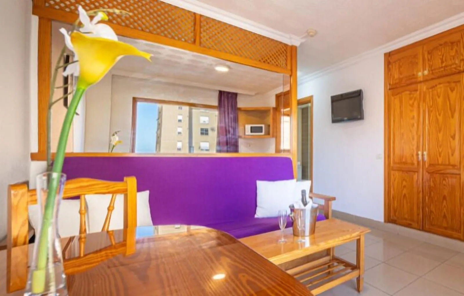 Skyview Hotel by LIVVO: A room with a wooden dining table, purple sofa, and wooden cabinets