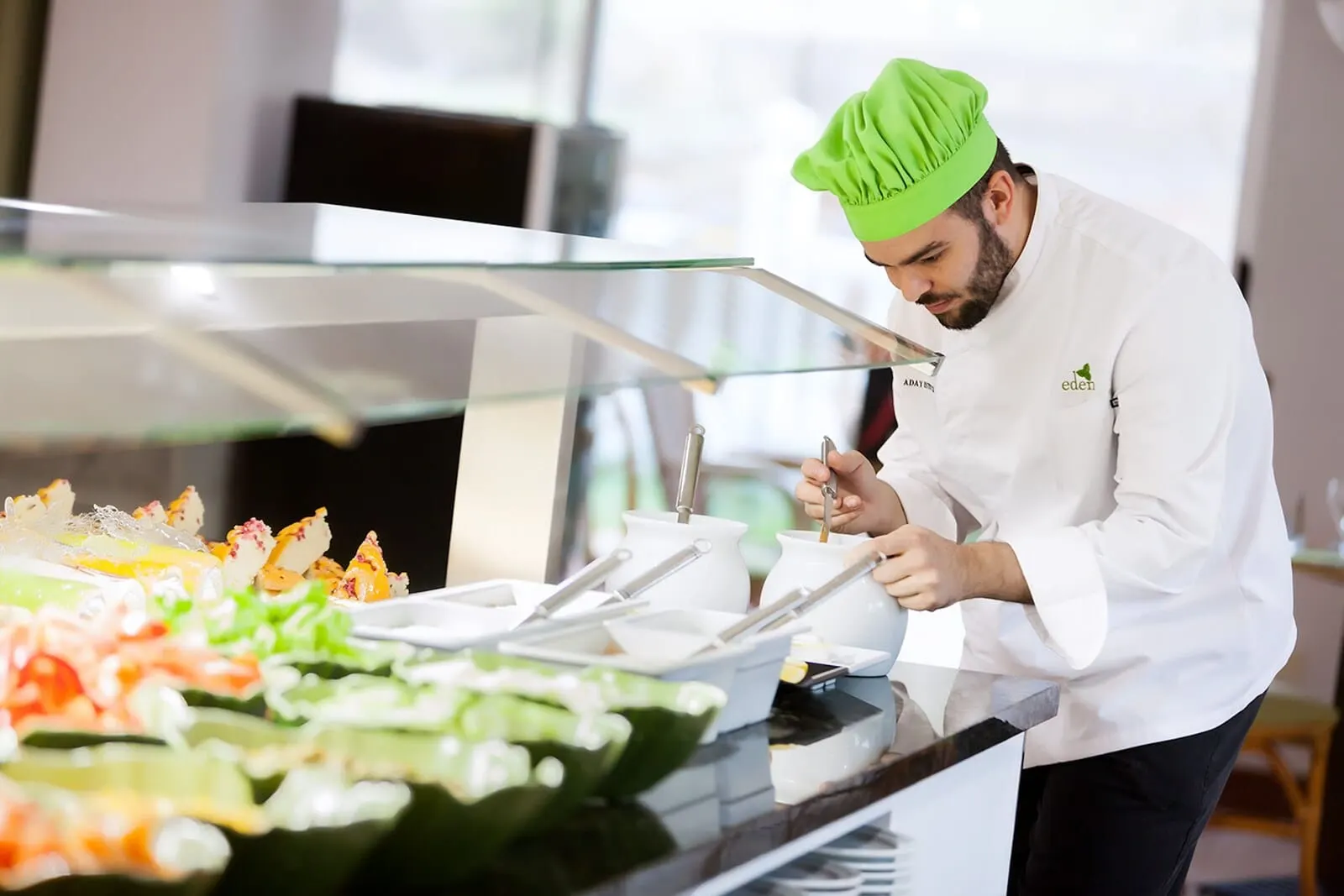 Parque Vacacional Eden: A chef in a white uniform and green hat preparing food at a buffet