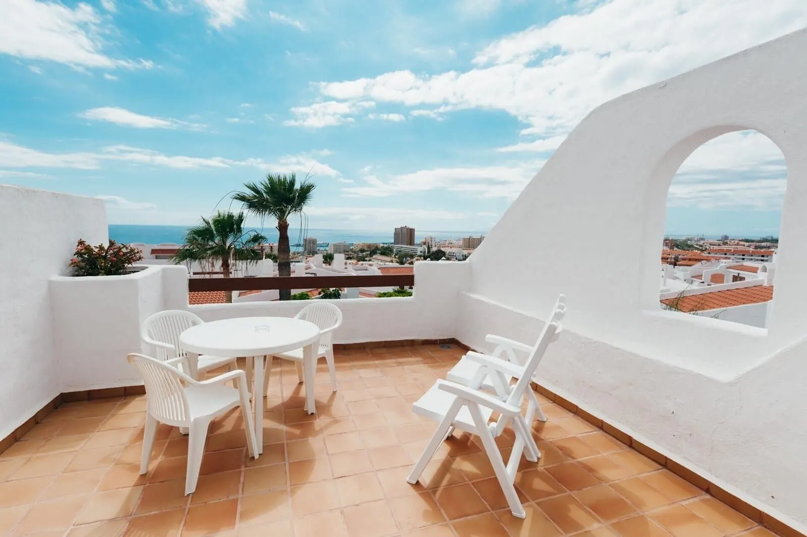 Ona Beverly Hills Suites: A terrace with a white table and chairs, a view of the city, and a palm tree
