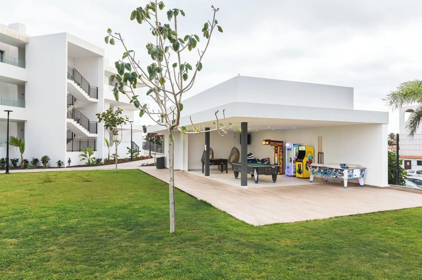 Amarilla Golf Residences: A modern building with a covered outdoor area featuring a pool table, arcade games