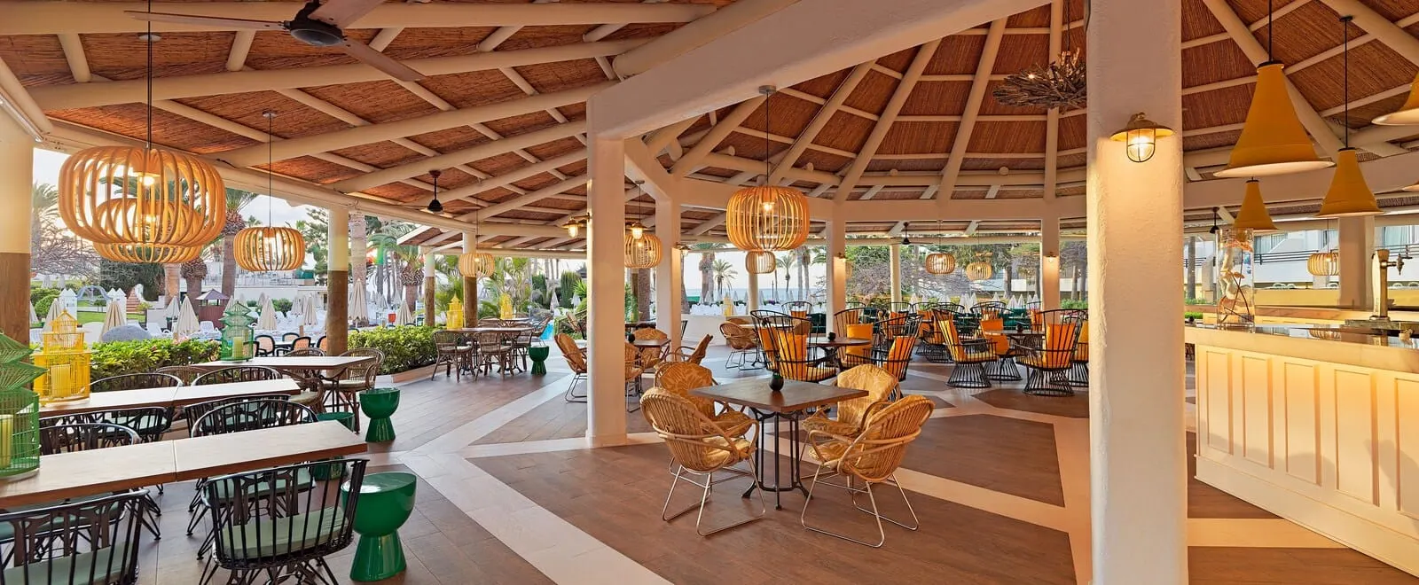 H10 Las Palmeras: An outdoor dining area with wooden tables and chairs, hanging pendant lights