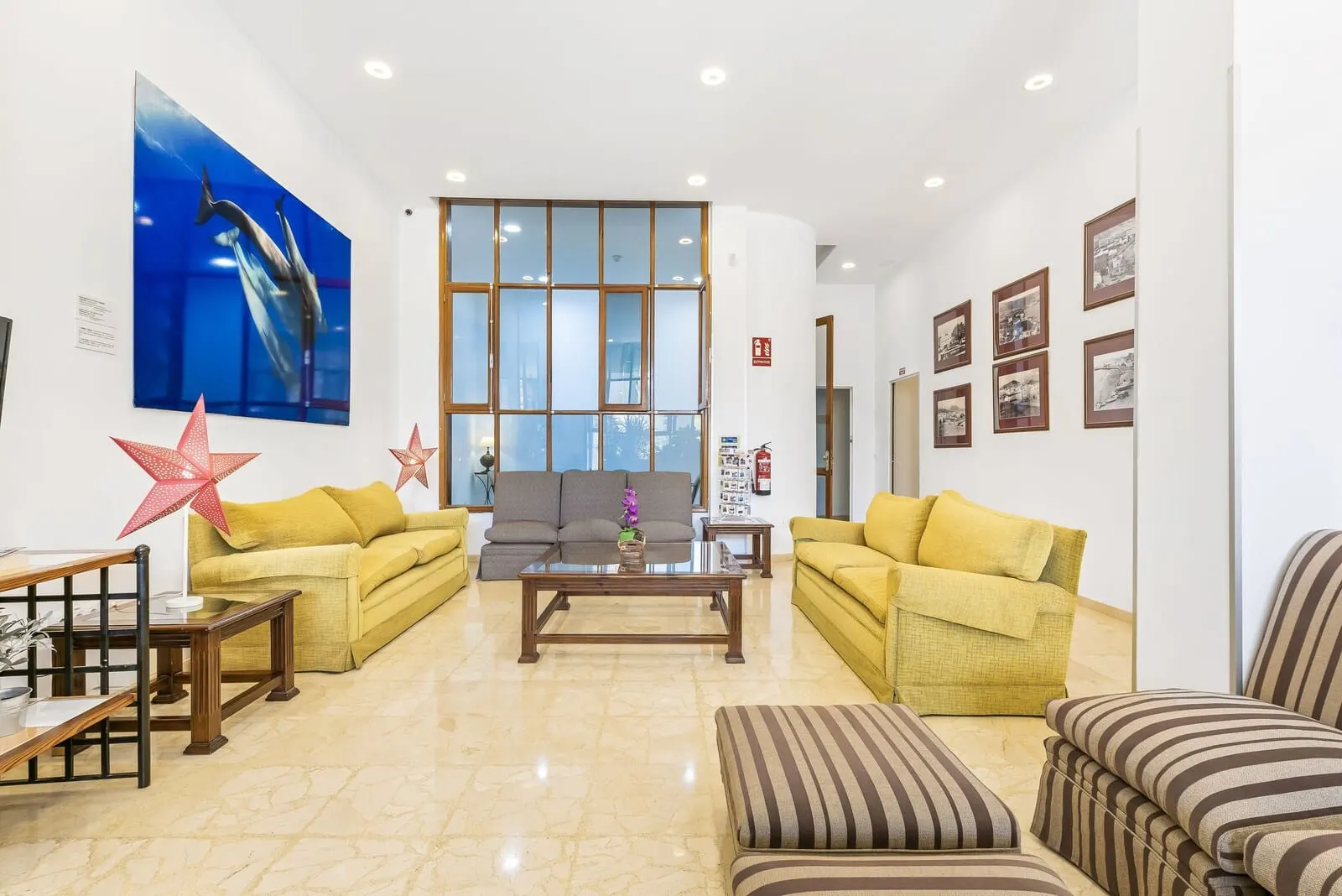 Andrea's Hotel Tenerife: A spacious lobby with a large window, two sofas, a coffee table, and a striped ottoman