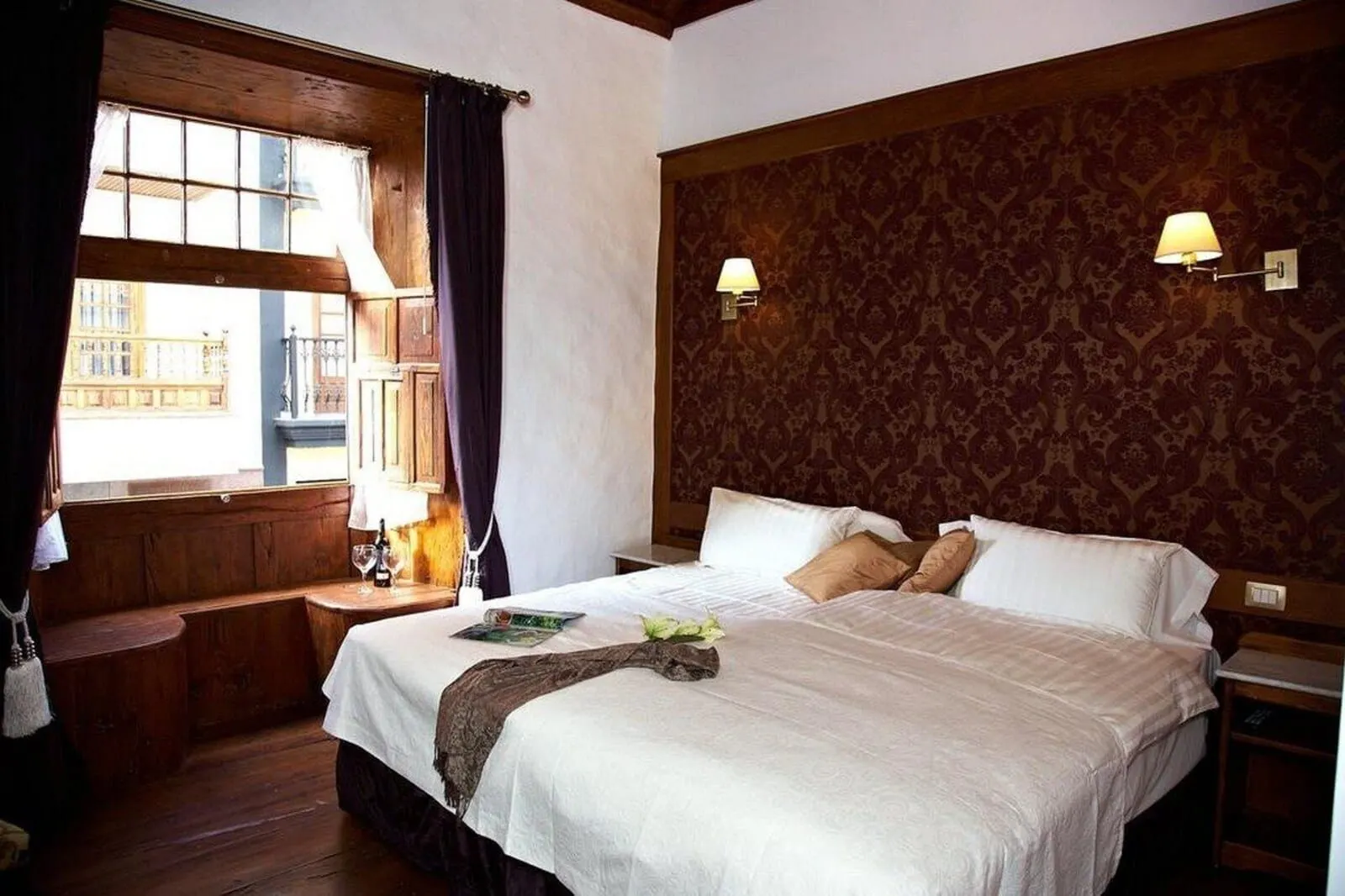 Hotel Emblemático San Agustín: A hotel room with a large bed, wooden bench, two bedside lamps