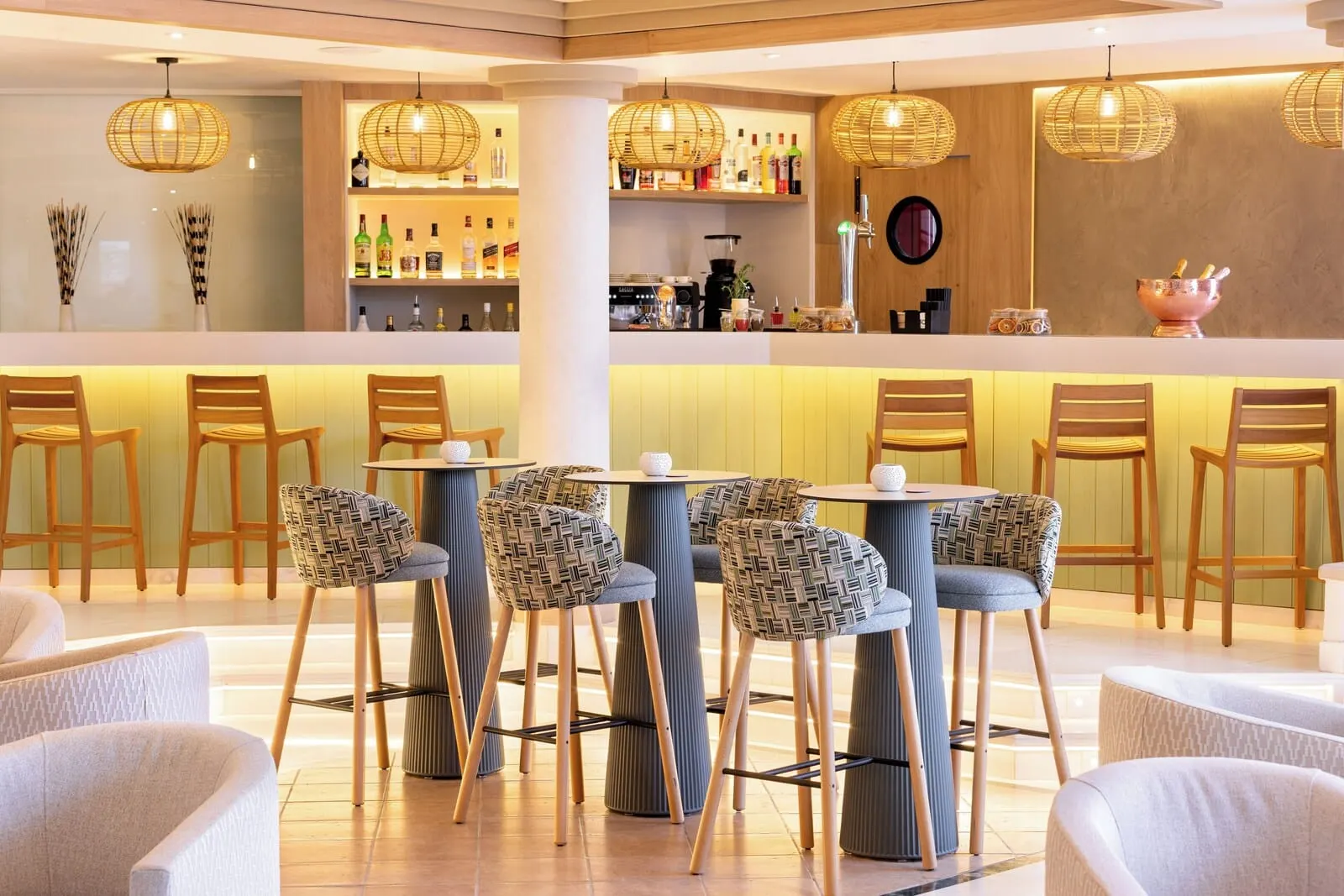 Sol Sun Beach Apartamentos: A bar area with wicker chairs, a bar counter, and hanging wicker light fixtures