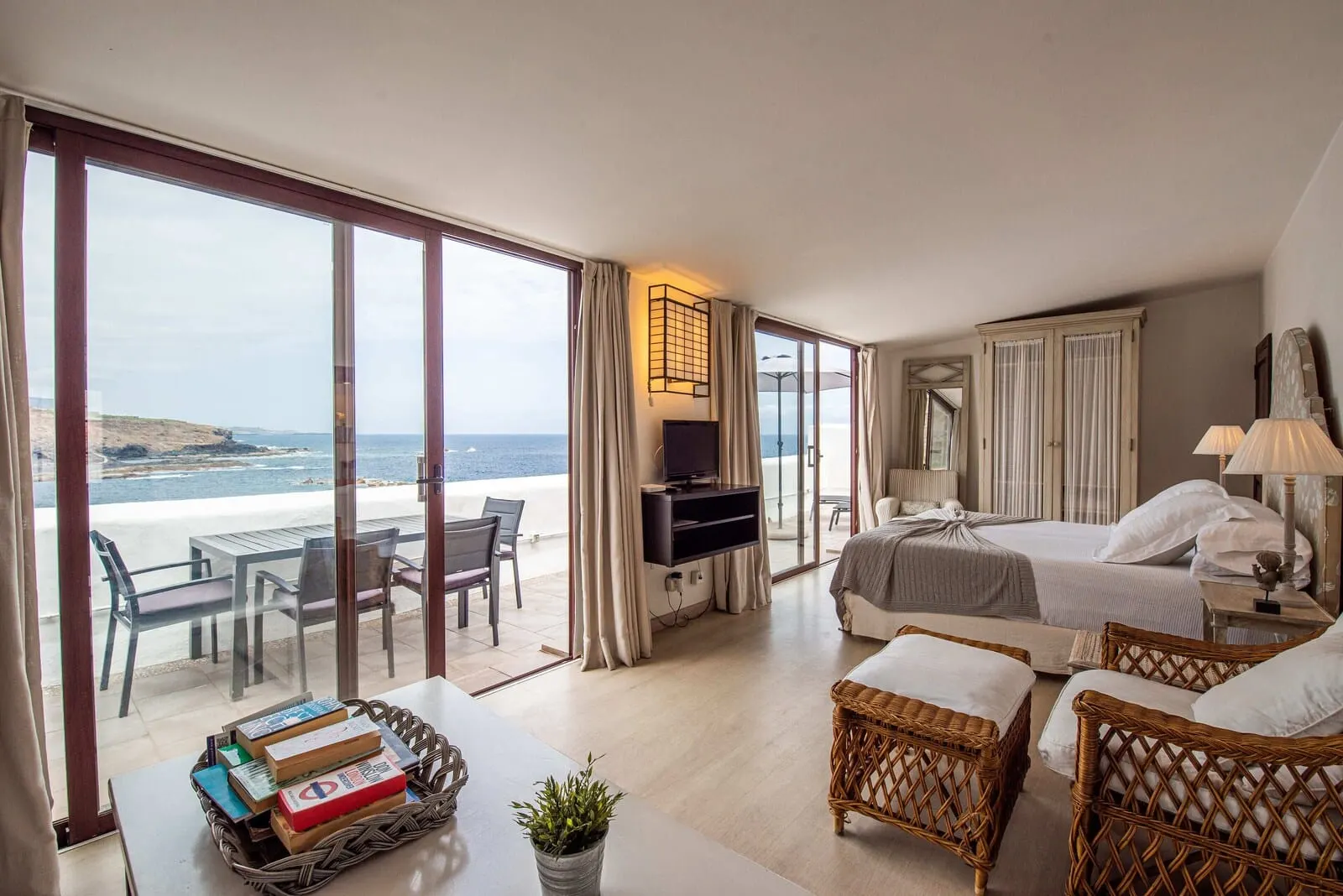 Isla Baja Suites: A hotel room with a large sliding glass door to the beach, a bed, a TV