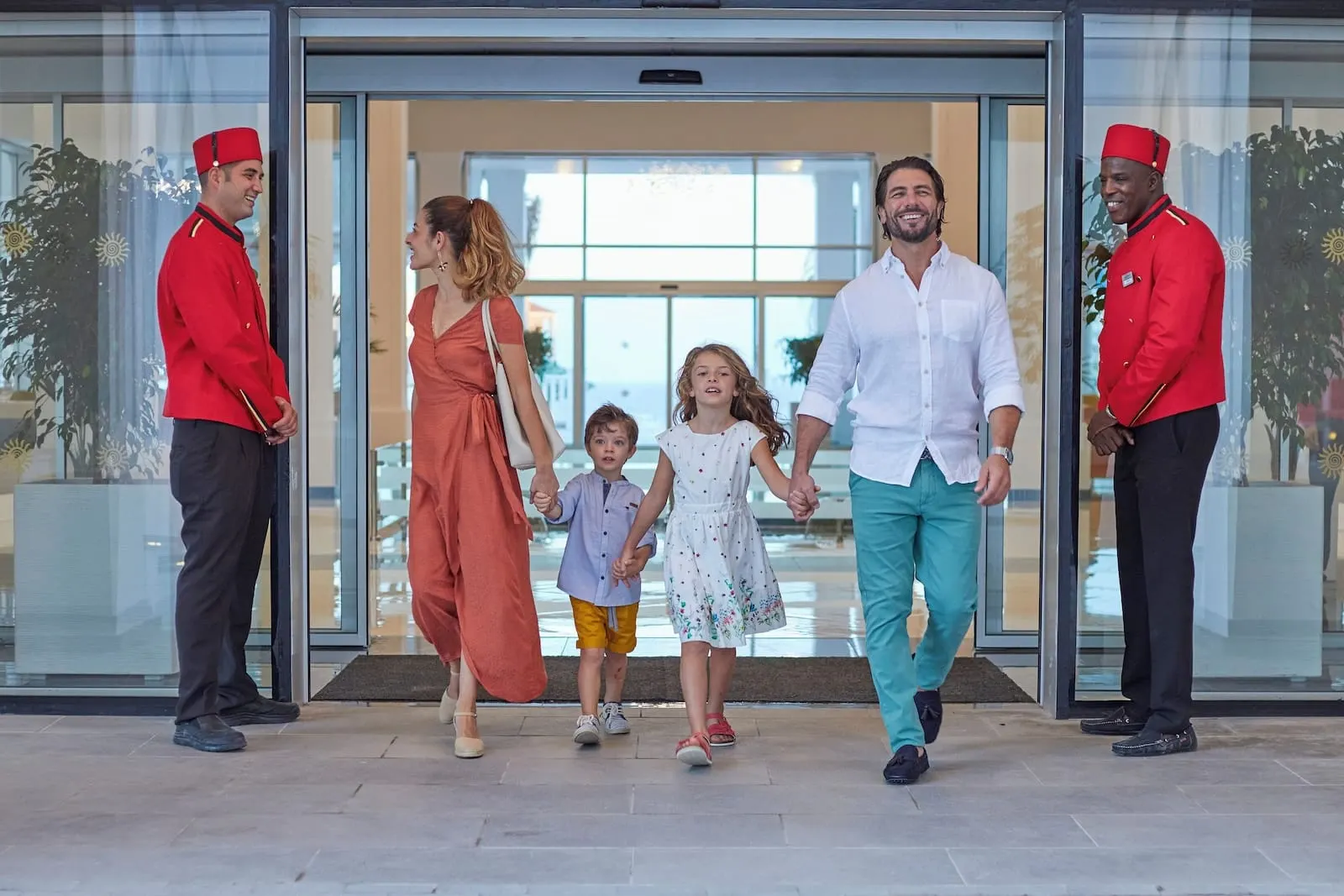 Bahia Principe Explore Fantasia: A family walking through a hotel entrance with staff members