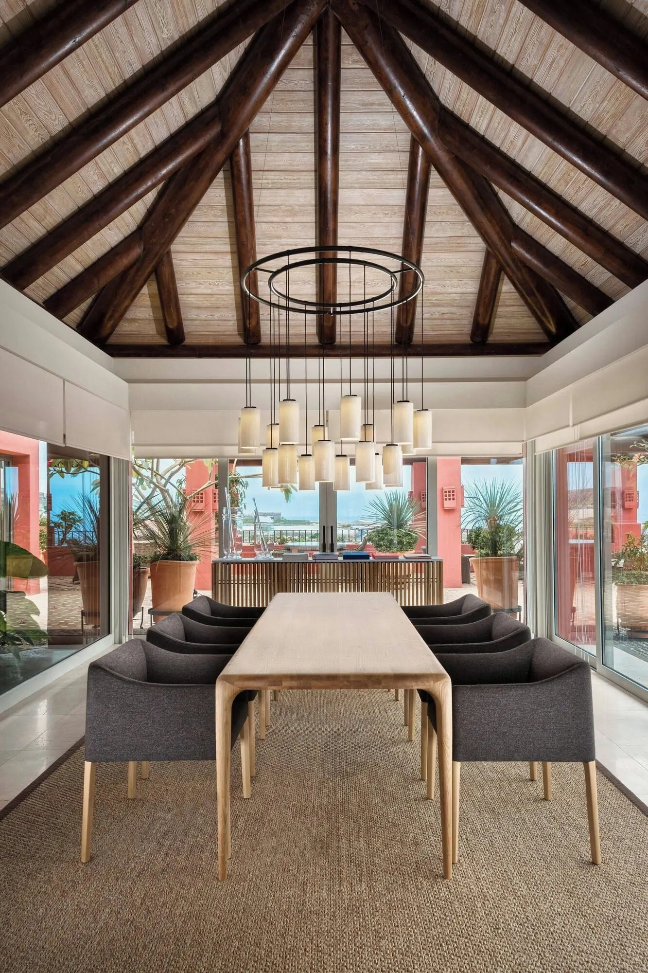 The Ritz-Carlton Tenerife, Abama: A modern dining area with a high ceiling, wooden beams, and a central table with chairs