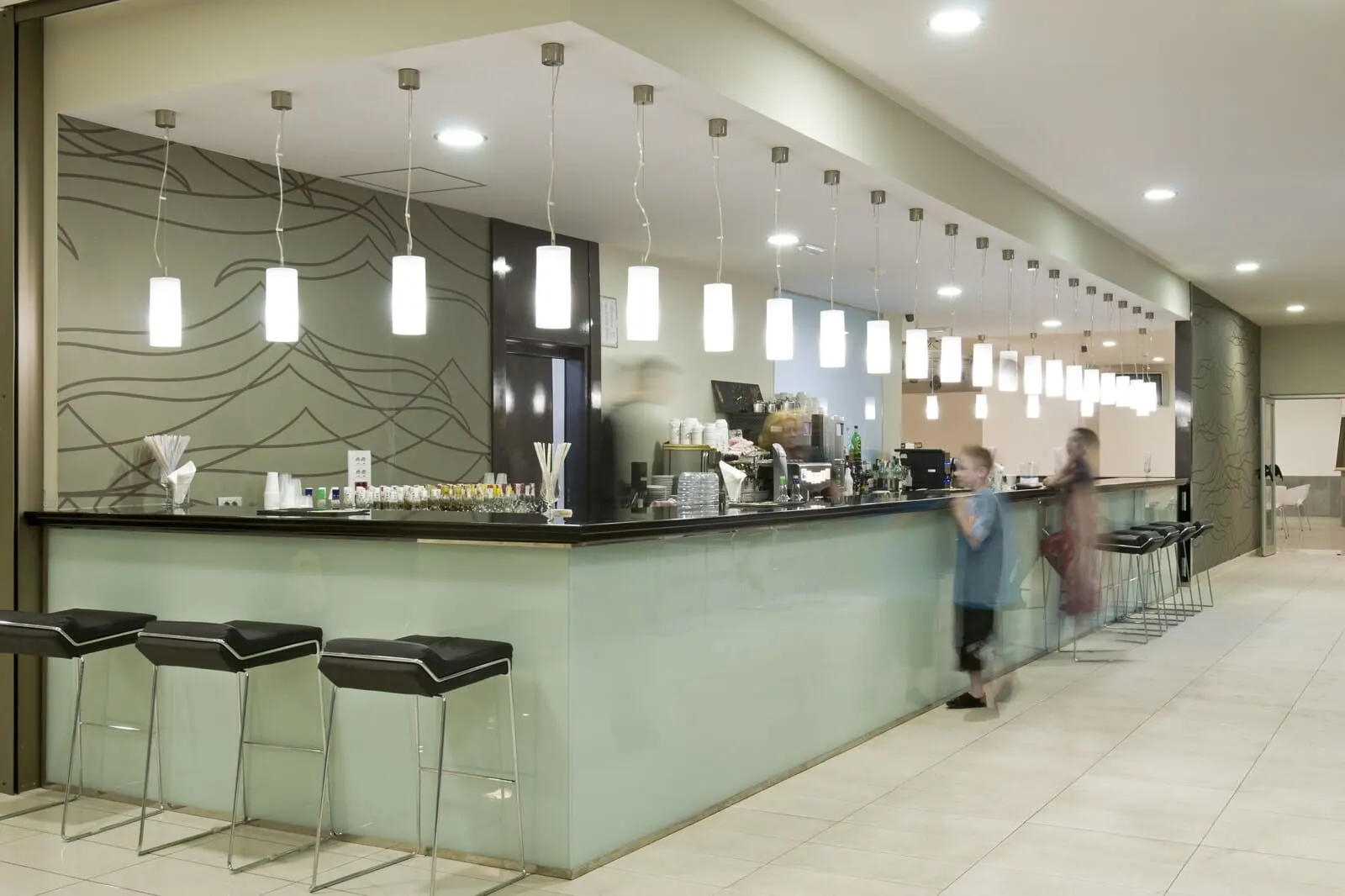 KN Aparthotel Columbus: A bar area with a counter, stools, and hanging pendant lights