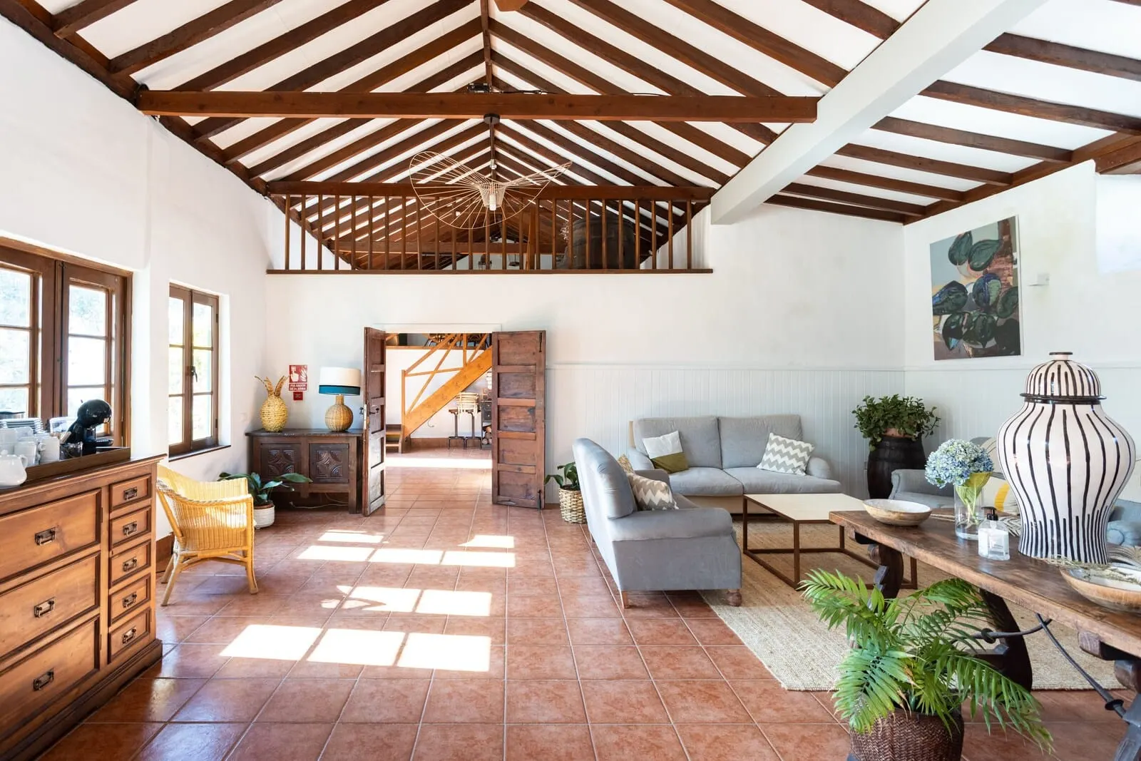 Hotel El Patio: A spacious living area with a high ceiling, wooden beams, a staircase, a sofa