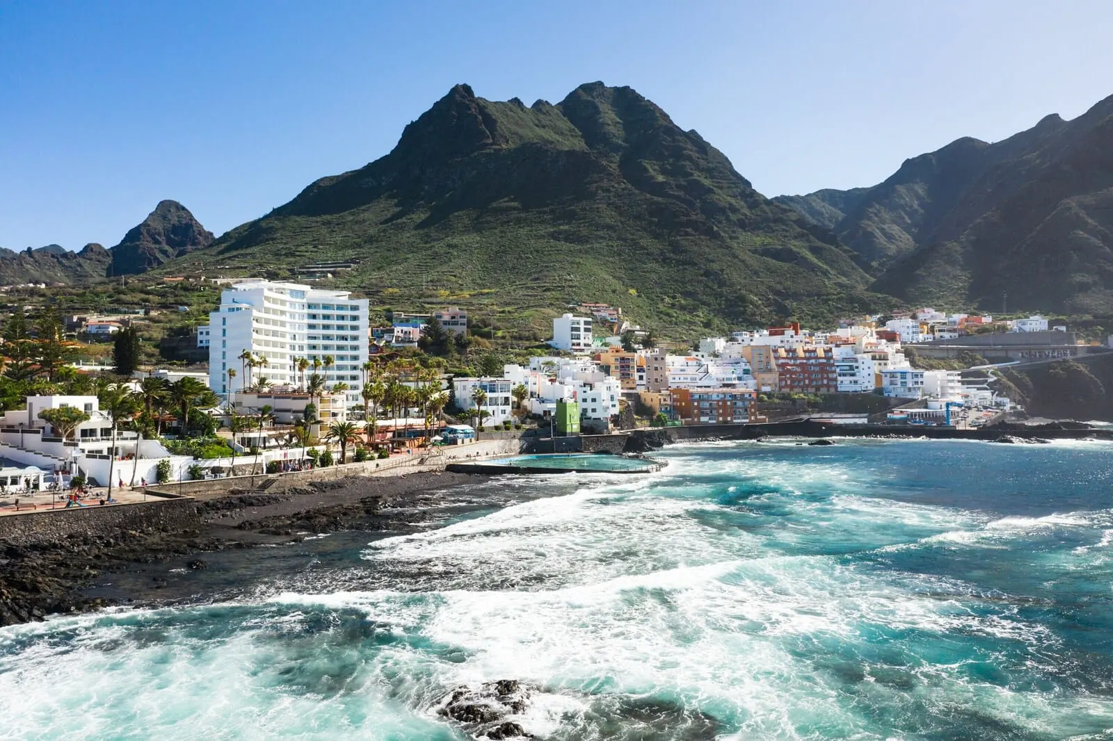 Océano Health Spa Hotel: A coastal town with buildings along the shoreline, a rocky beach