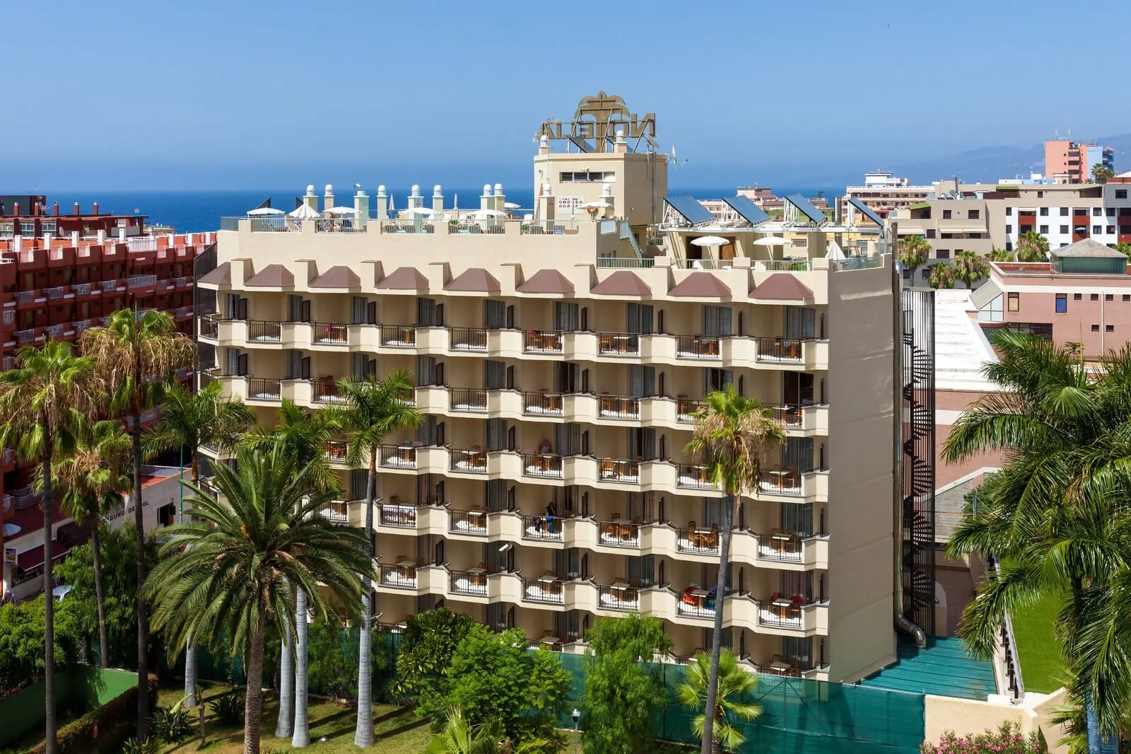 GF Noelia: A multi-story hotel with balconies, a pool, and a view of the sea