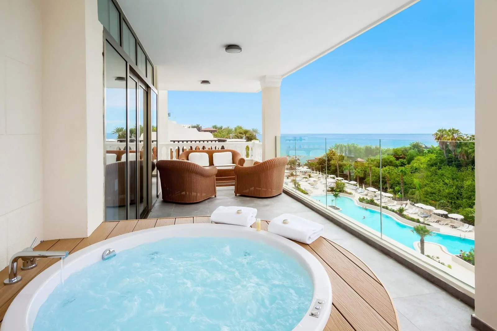 Gran Tacande Wellness & Relax: A balcony with a hot tub, wicker chairs, and a view of a pool and ocean
