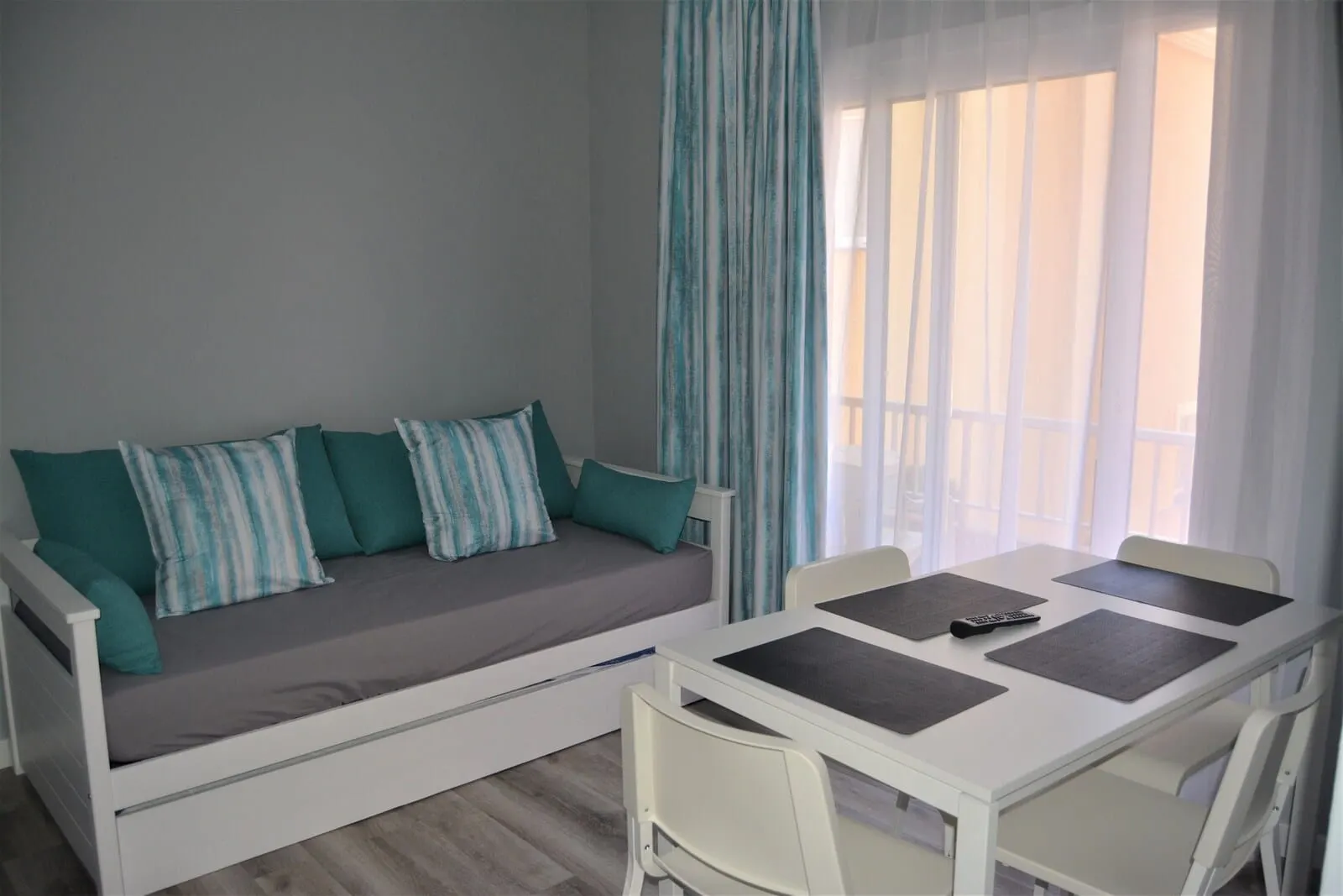 RF Apartamentos Bambi: A room with a sofa bed, a dining table with chairs, and a window with curtains