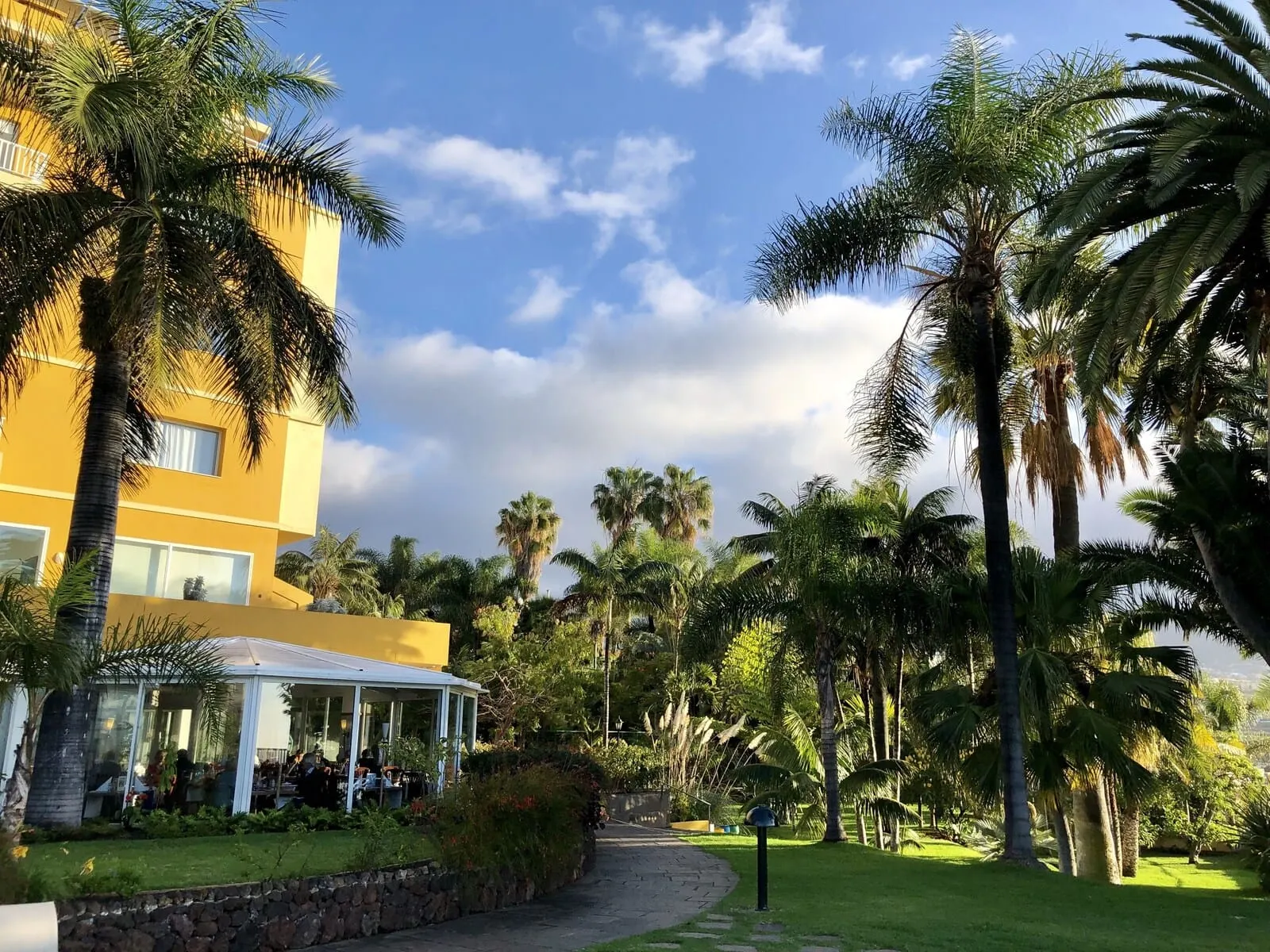 Hotel Tigaiga: A resort with a yellow building, palm trees, and a covered outdoor seating area