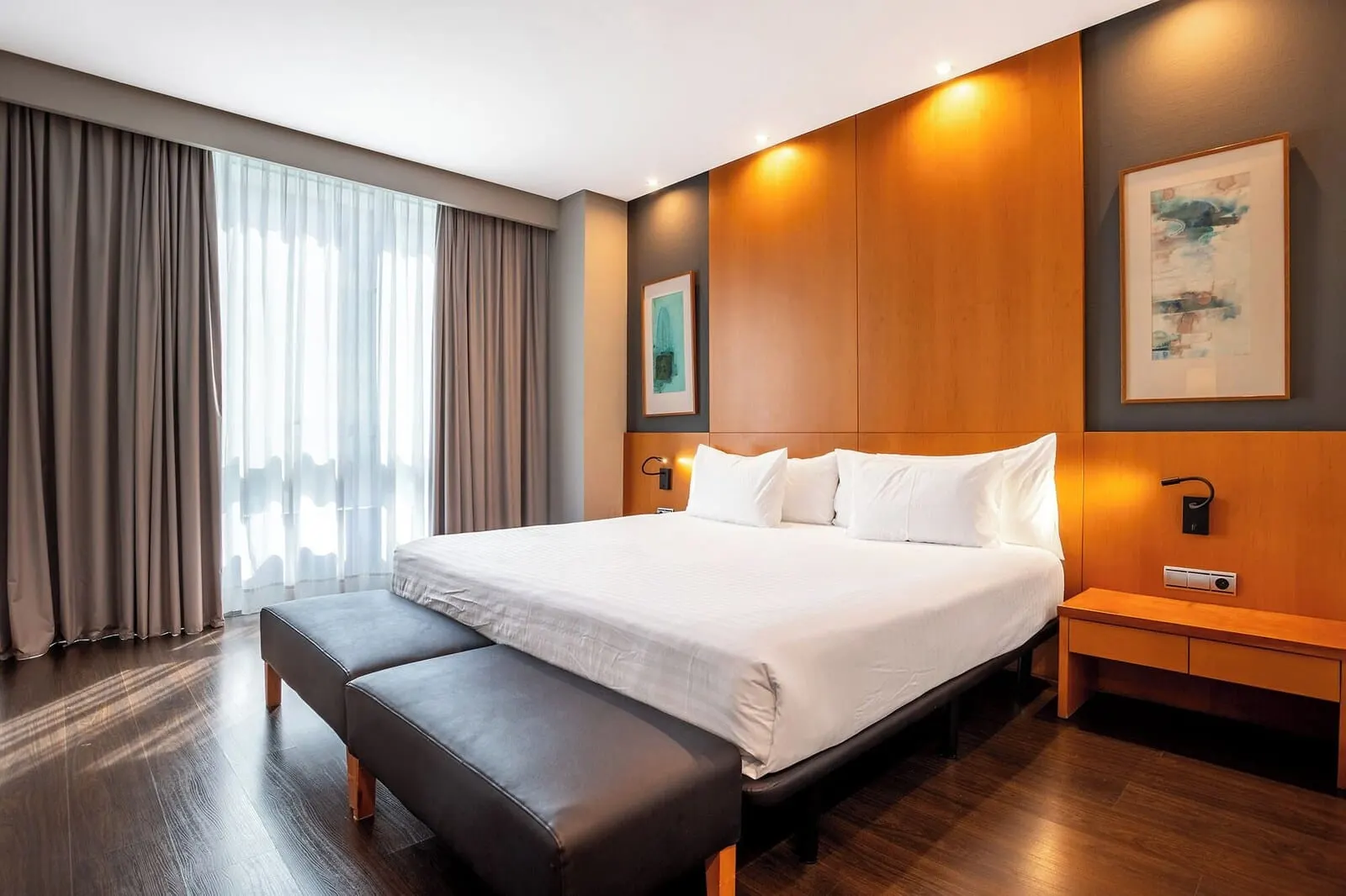 Eurostars Atlántida: A modern hotel room with a large bed, a bench, a nightstand, and a painting on the wall