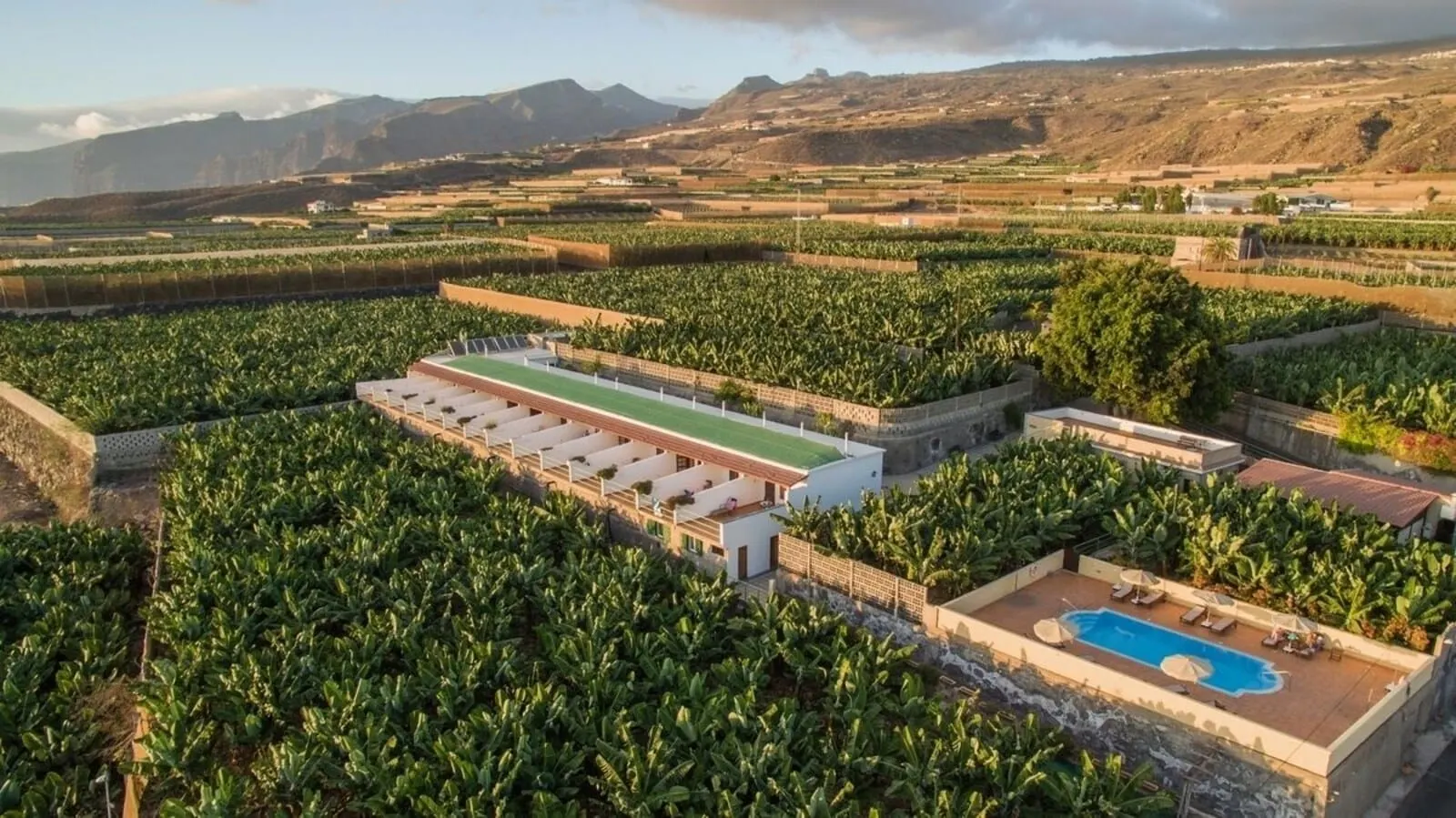 Hotel Rural El Navío: A large building with a long, flat roof terrace surrounded by lush green fields