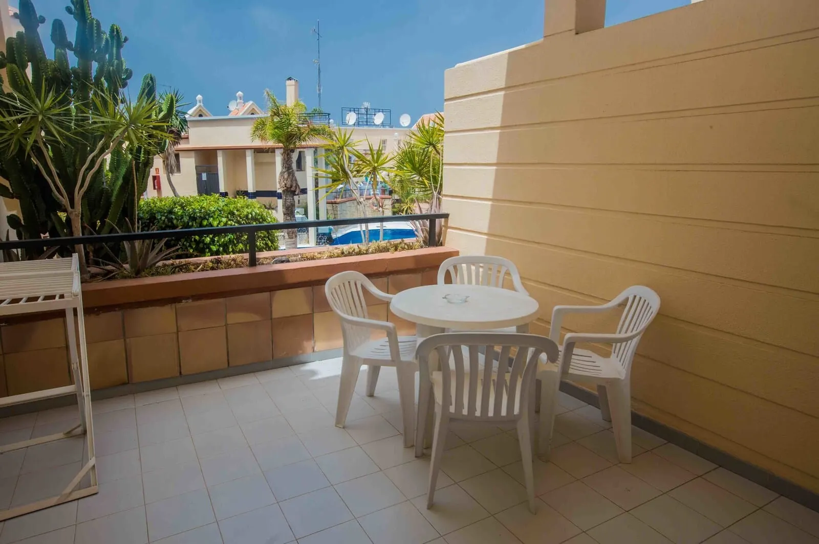 Yucca Park Aparthotel: A balcony with a white table and chairs, a railing