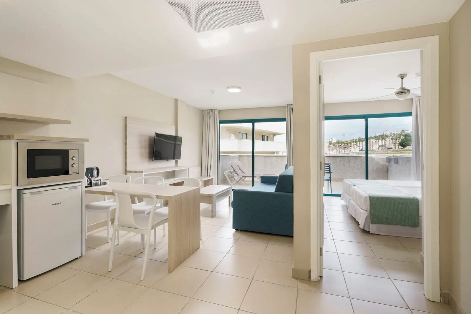 Alua Tenerife: A modern hotel room with a kitchenette, a dining area, a balcony with a view