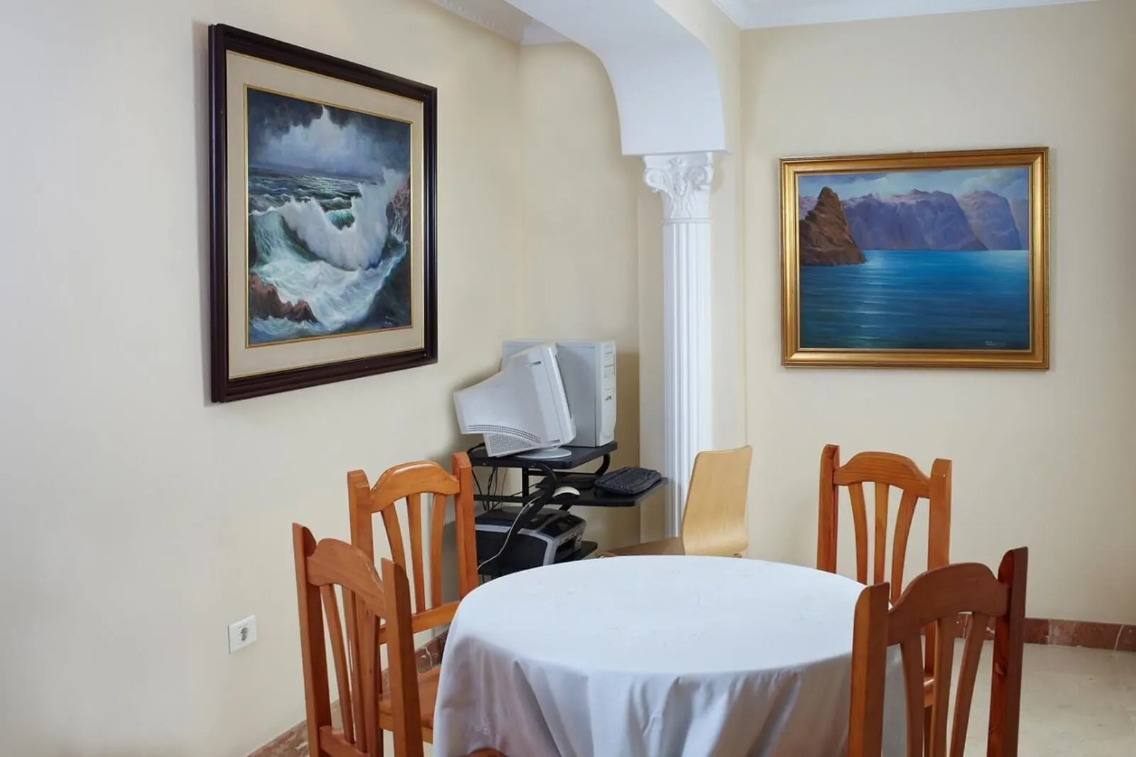 Hotel Tanausú: A dining area with a round table, wooden chairs, and two framed paintings on the wall
