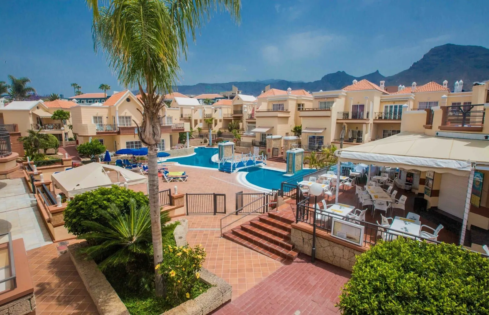 Yucca Park Aparthotel: A resort with a swimming pool, outdoor seating, and a view of mountains