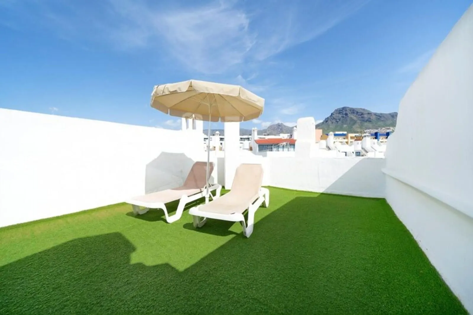 BLUESEA Bahía Fañabé Villas: A rooftop terrace with artificial grass, two lounge chairs, and a single umbrella