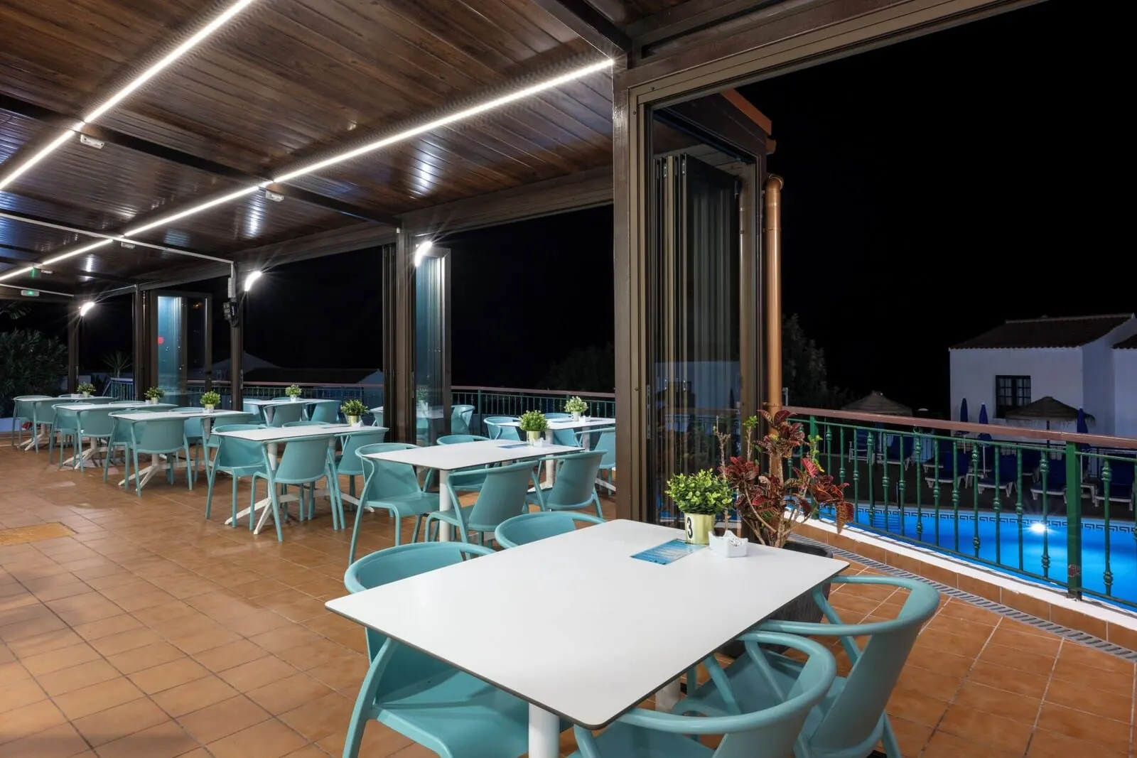 Ona Las Rosas: An outdoor dining area with tables and chairs, a pool in the background