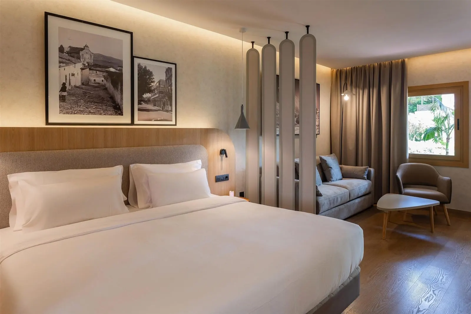 Radisson Resort & Residences Tenerife: A hotel room with a large bed, a sofa, a chair, and a window with curtains