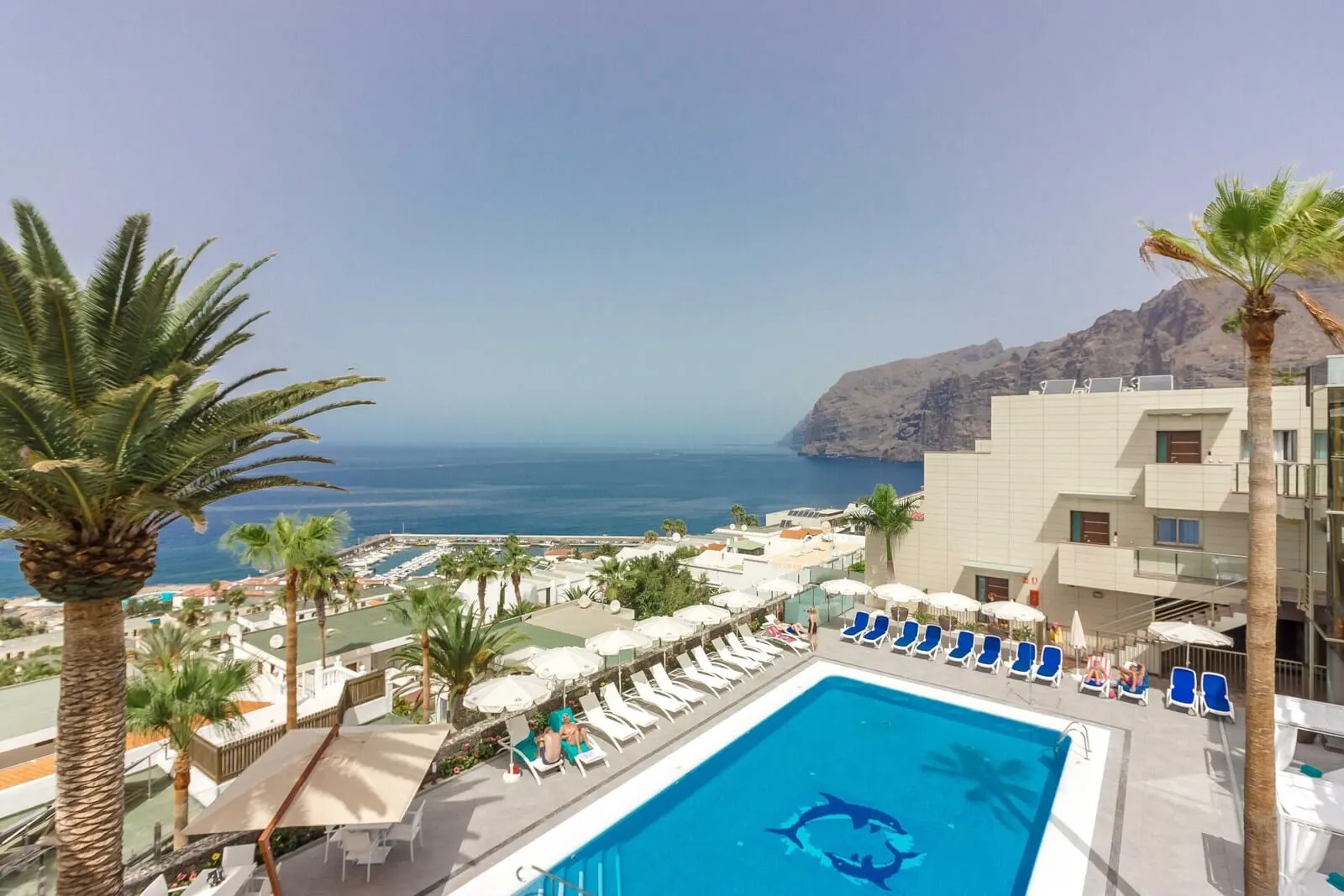 Klayman Diamond Aparthotel: A pool area with lounge chairs, umbrellas, and a view of the sea and mountains