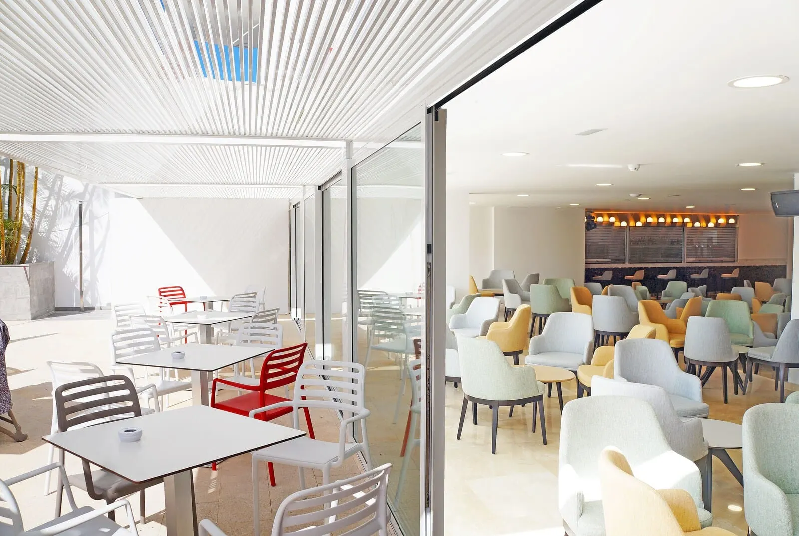 Alexandre Troya: A modern indoor dining area with white and colorful chairs, tables