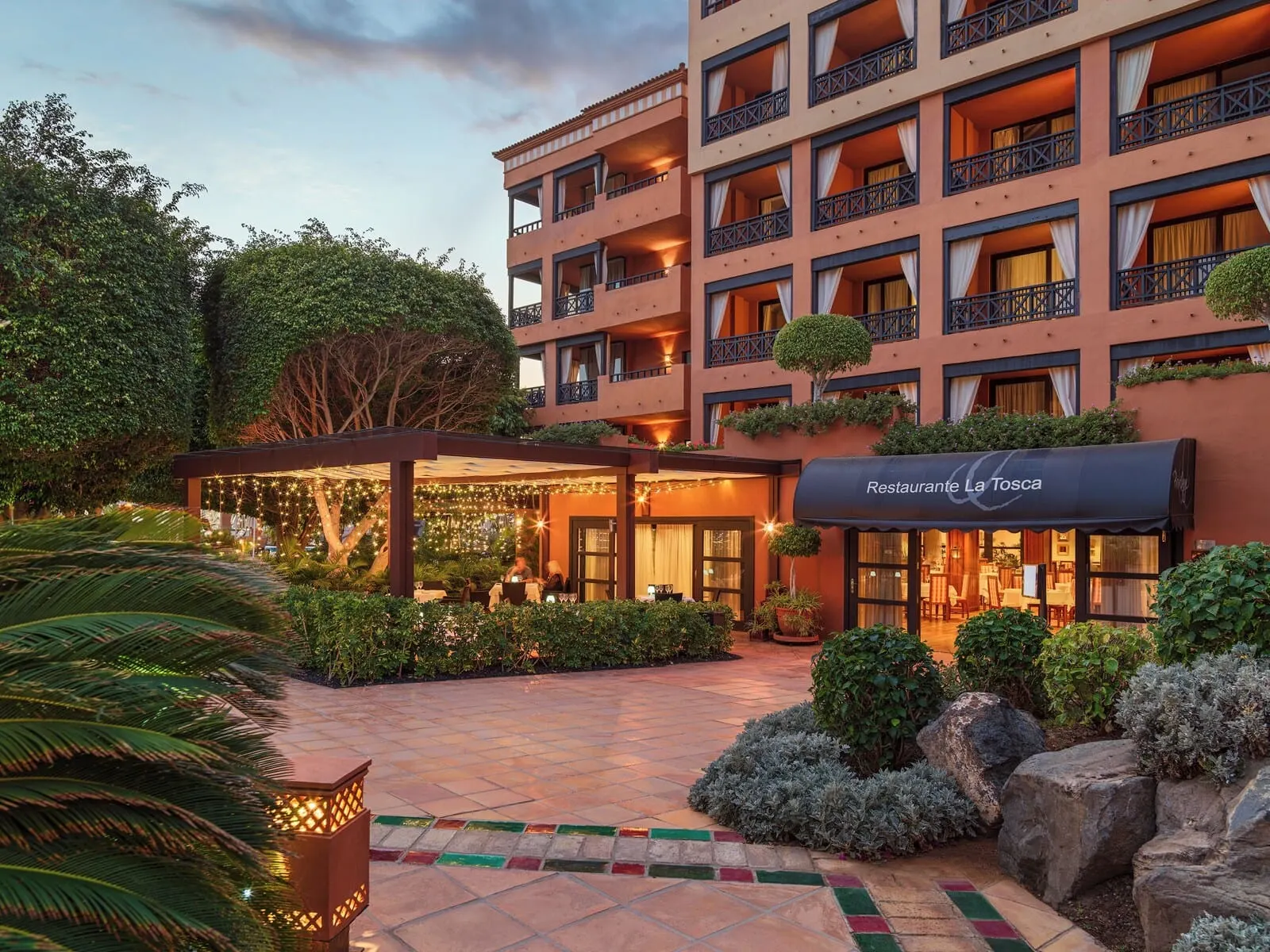 H10 Costa Adeje Palace: A hotel with multiple balconies, a covered outdoor seating area