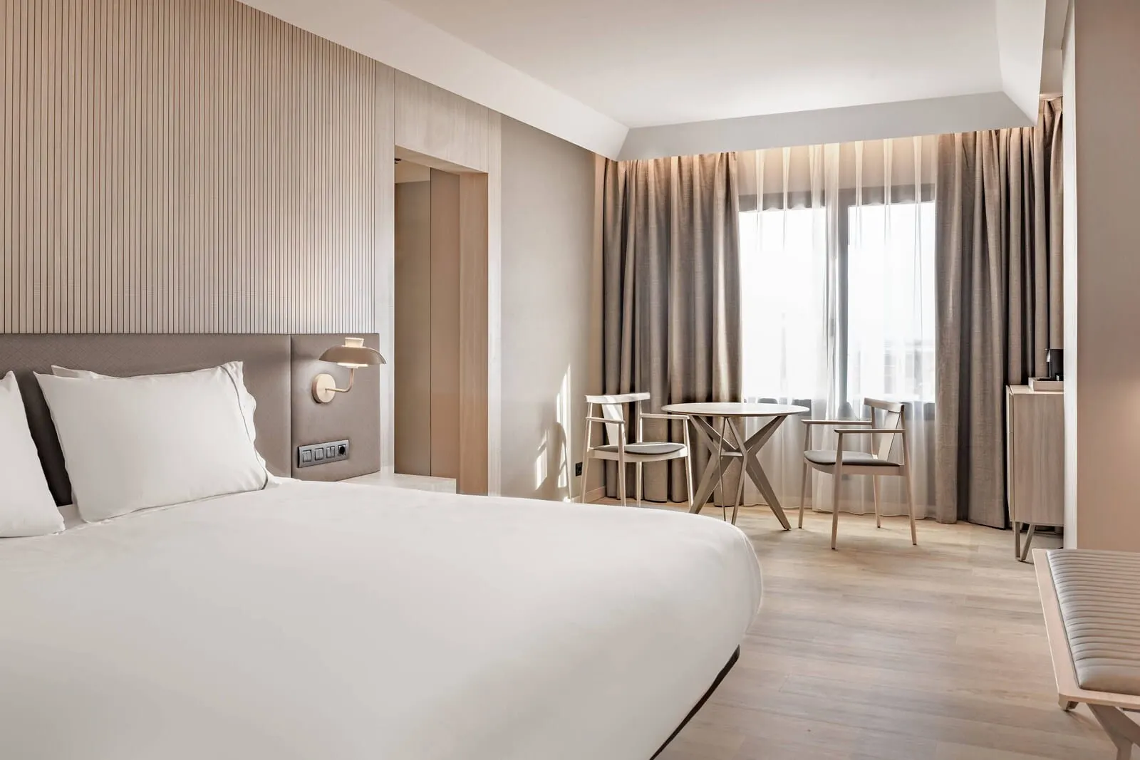 AC Hotel Tenerife: A modern hotel room with a large bed, a desk, and chairs, a small table