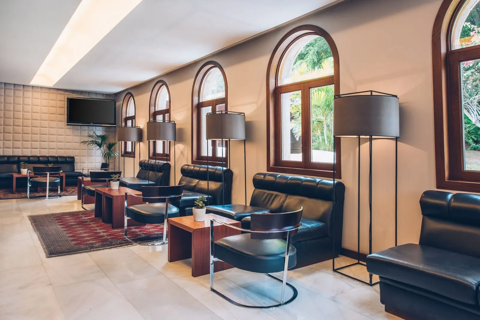 Iberostar Heritage Grand Mencey: A modern lounge with leather sofas, a flat-screen TV, and large floor lamps