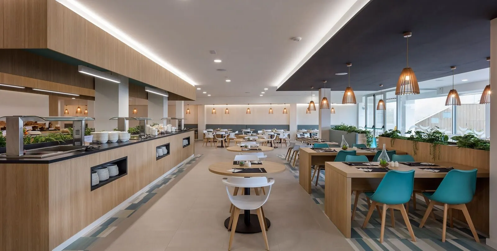 Ohasis Boutique Suites: A modern cafeteria with wooden accents, round tables, and pendant lighting