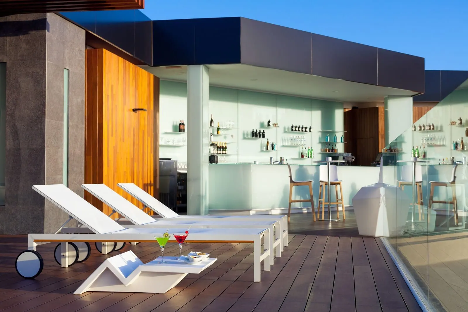 Tigotan Lovers & Friends: A modern outdoor bar area with lounge chairs, a bar counter, and a glass enclosure
