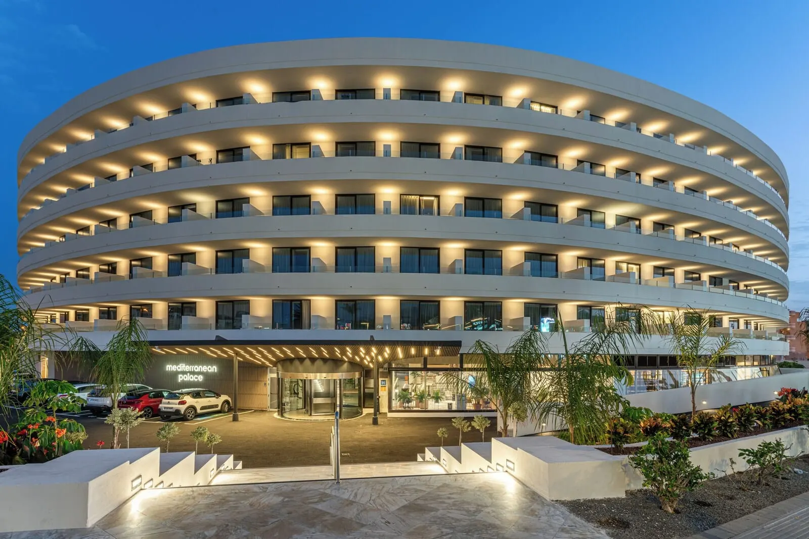 Mediterranean Palace: A modern hotel with a circular design, multiple balconies, and a well-lit entrance