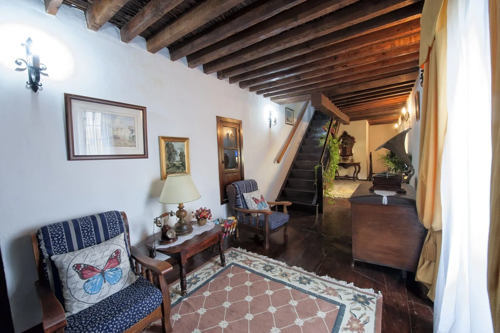 Hotel Rural Senderos de Abona: A cozy living room with wooden beams, a staircase, and a view of the garden