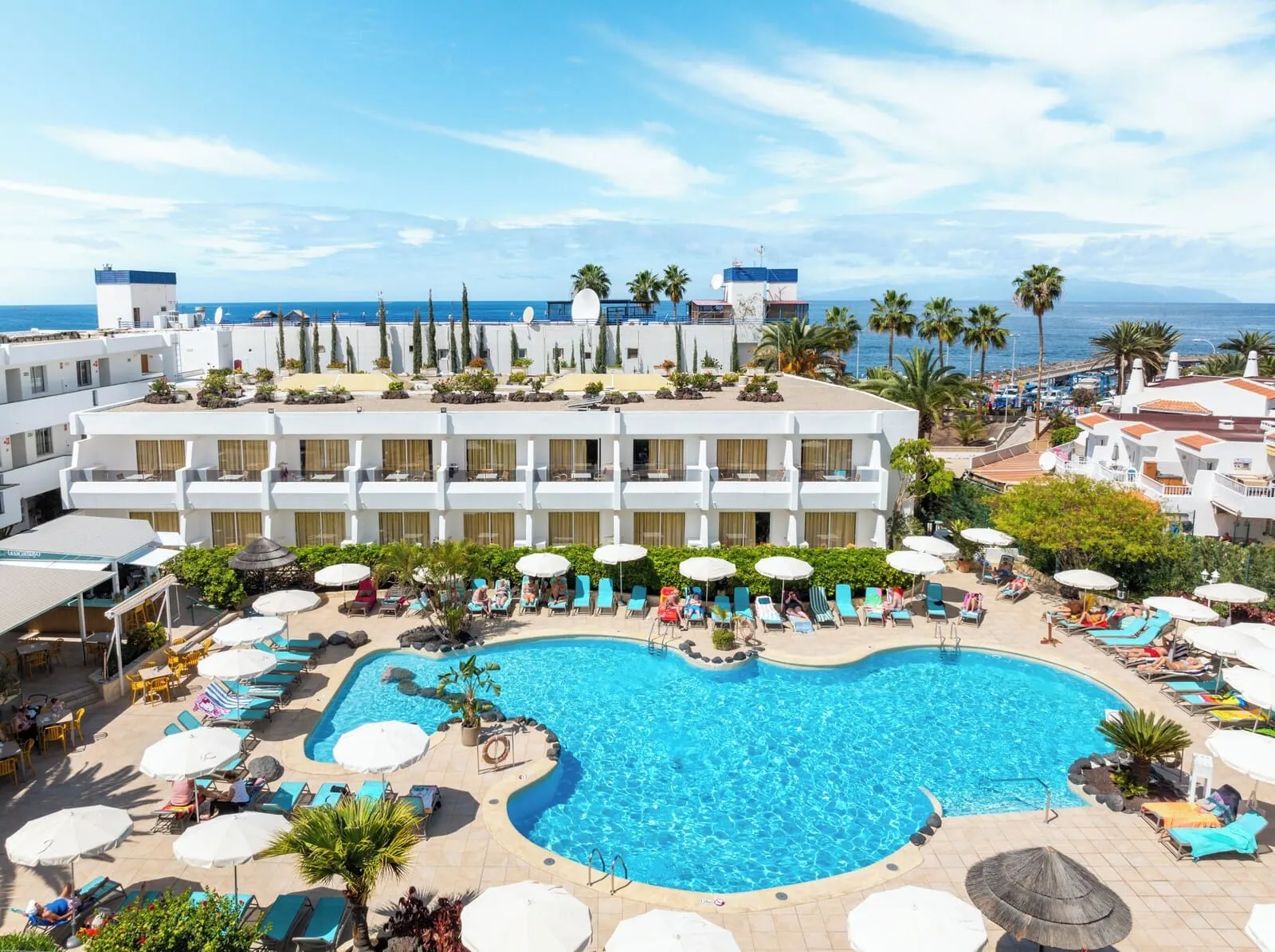 HOVIMA Panorama: A hotel with a rooftop pool surrounded by lounge chairs and umbrellas