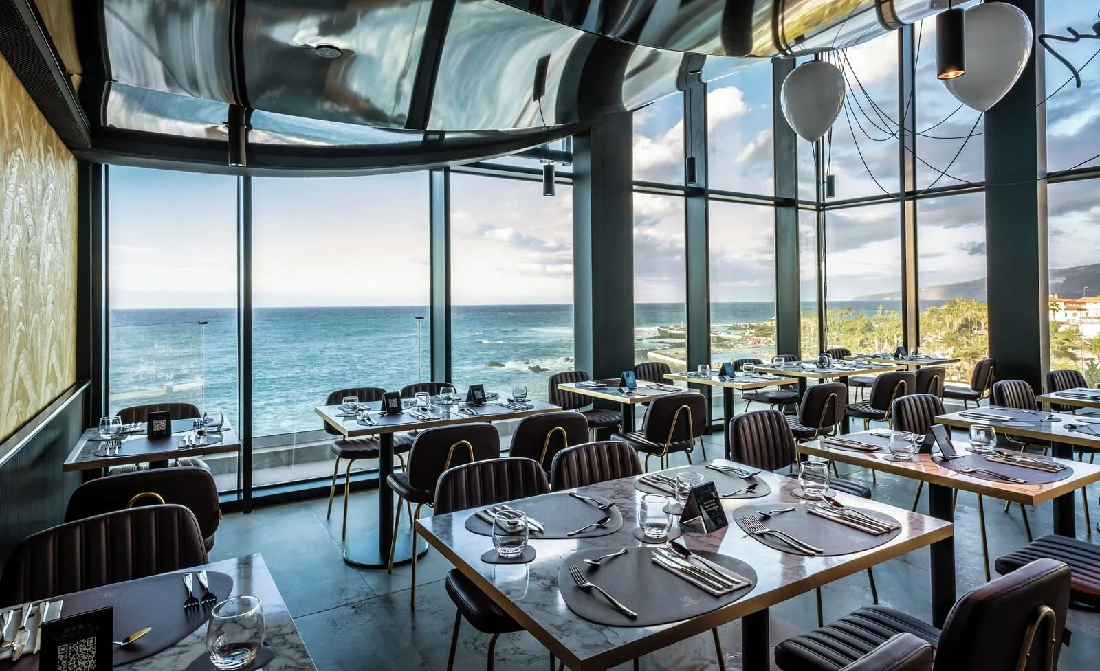 Silken Saaj Maar: A restaurant with tables set for dining, large windows offering ocean views