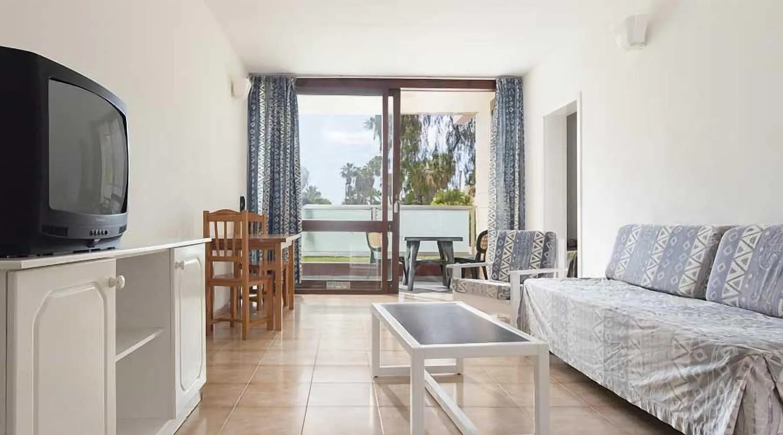 Hotel Palia Don Pedro: A room with a TV, a sofa, a dining table with chairs, and a balcony with curtains