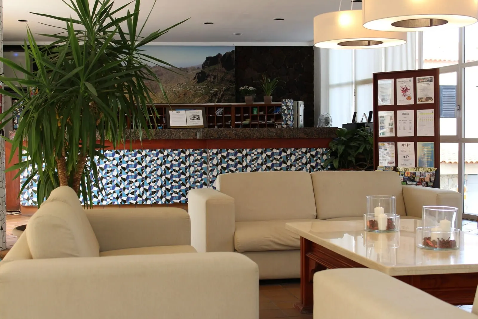Vigilia Park: A lobby with a sofa, a table with candles, a large plant, and a patterned wall