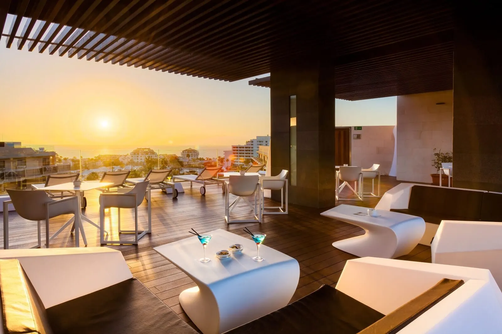 Tigotan Lovers & Friends: A rooftop lounge with white furniture, a wooden deck, and a sunset view