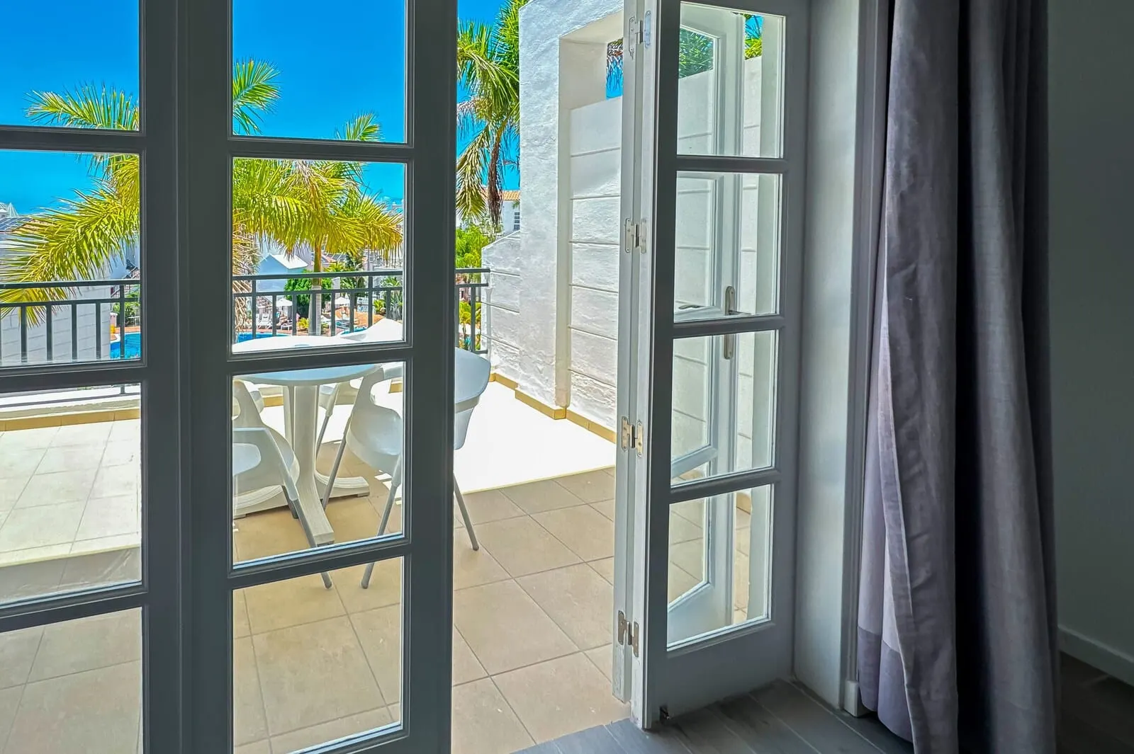 Apartamentos Parque del Sol: An open balcony with a view of palm trees and a pool