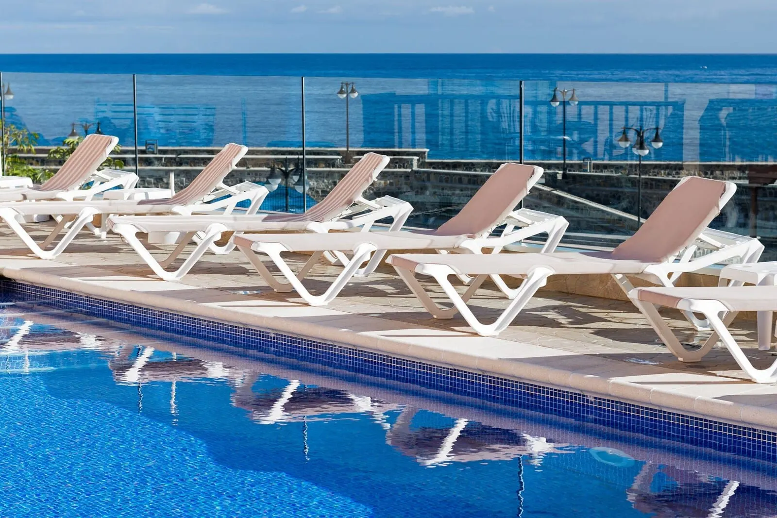 Hotel Monopol: A poolside area with lounge chairs and a view of the ocean
