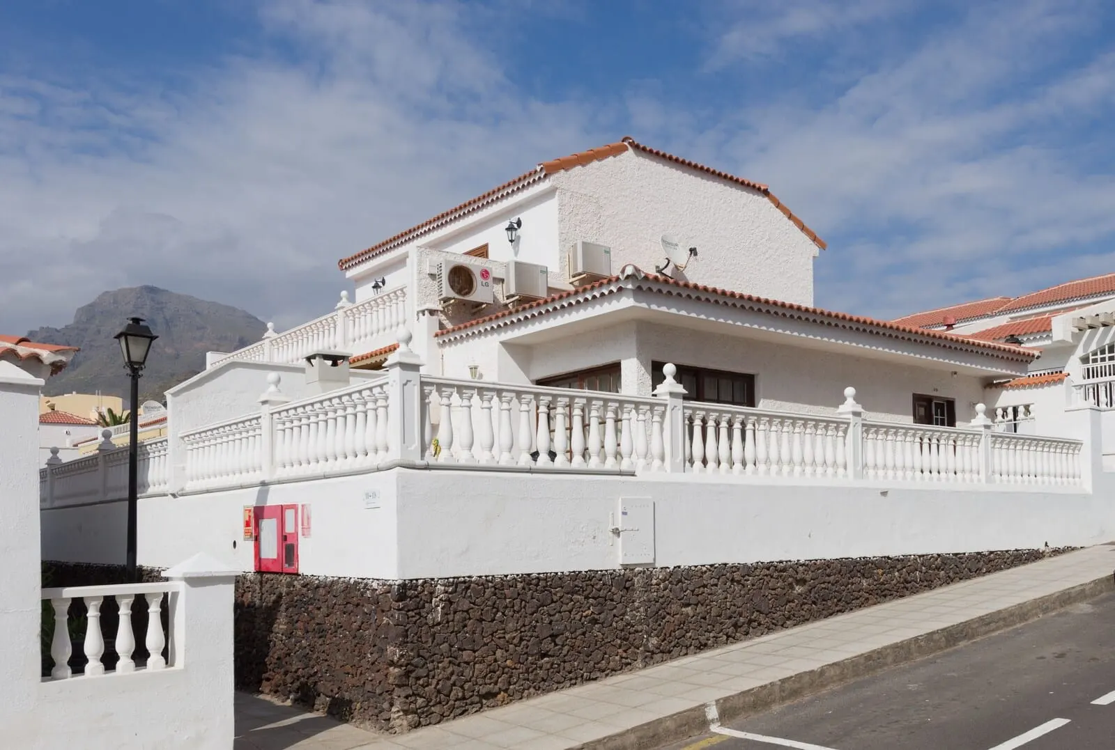 Tinerfe Garden: A white building with a red-tiled roof, a stone wall, and a white balcony railing