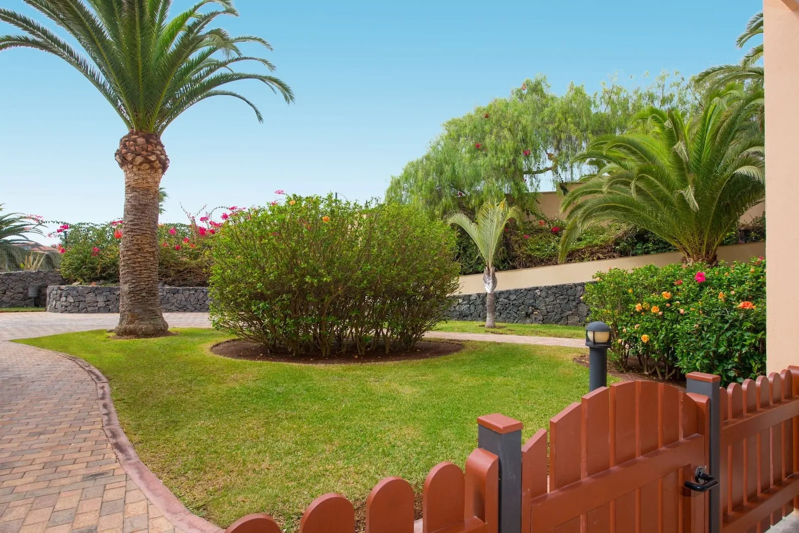Iberostar Selection Anthelia: A landscaped garden with palm trees, a brick pathway, and a wooden fence